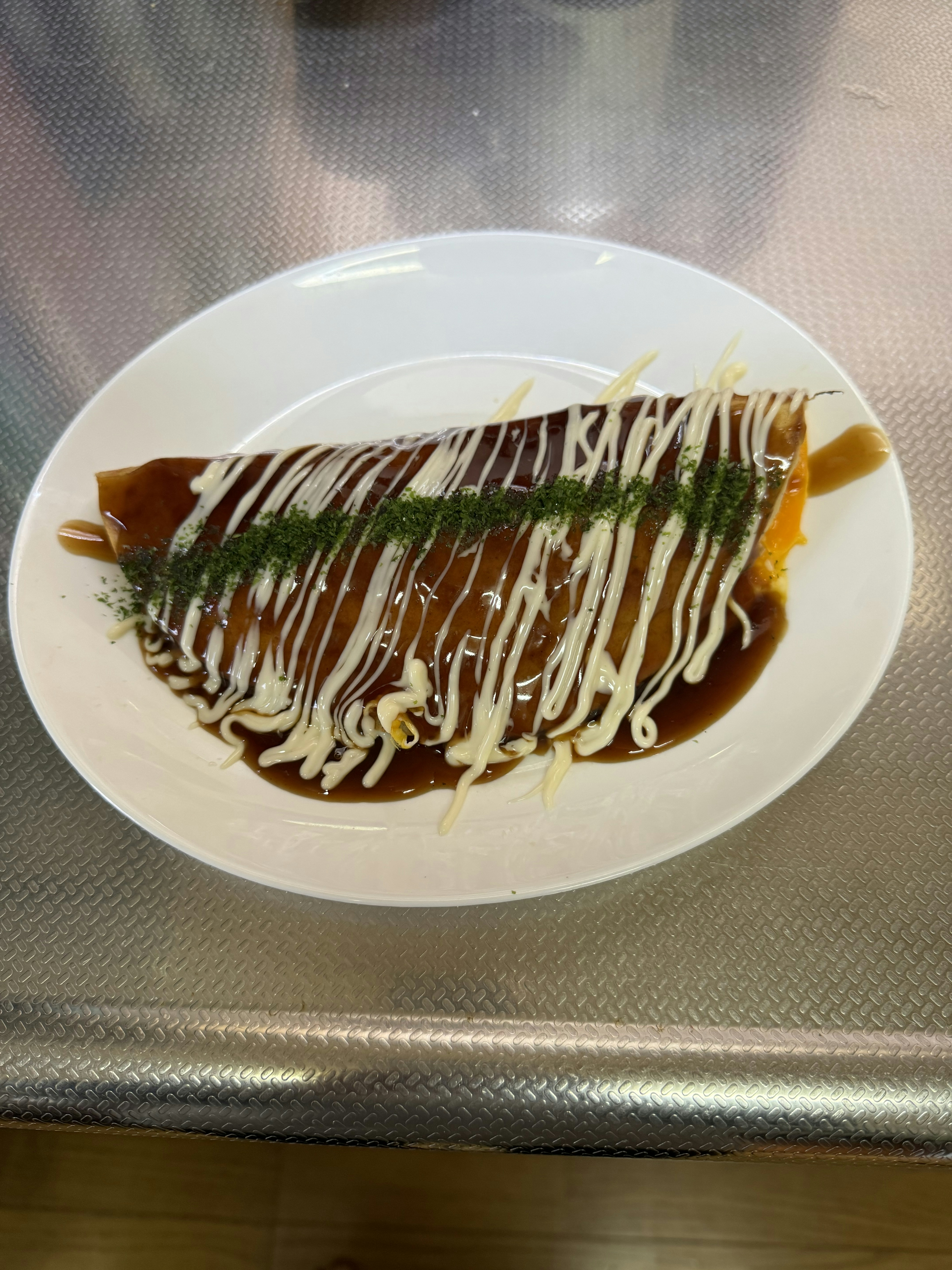 Omelette rice on a plate with sauce and mayonnaise drizzle