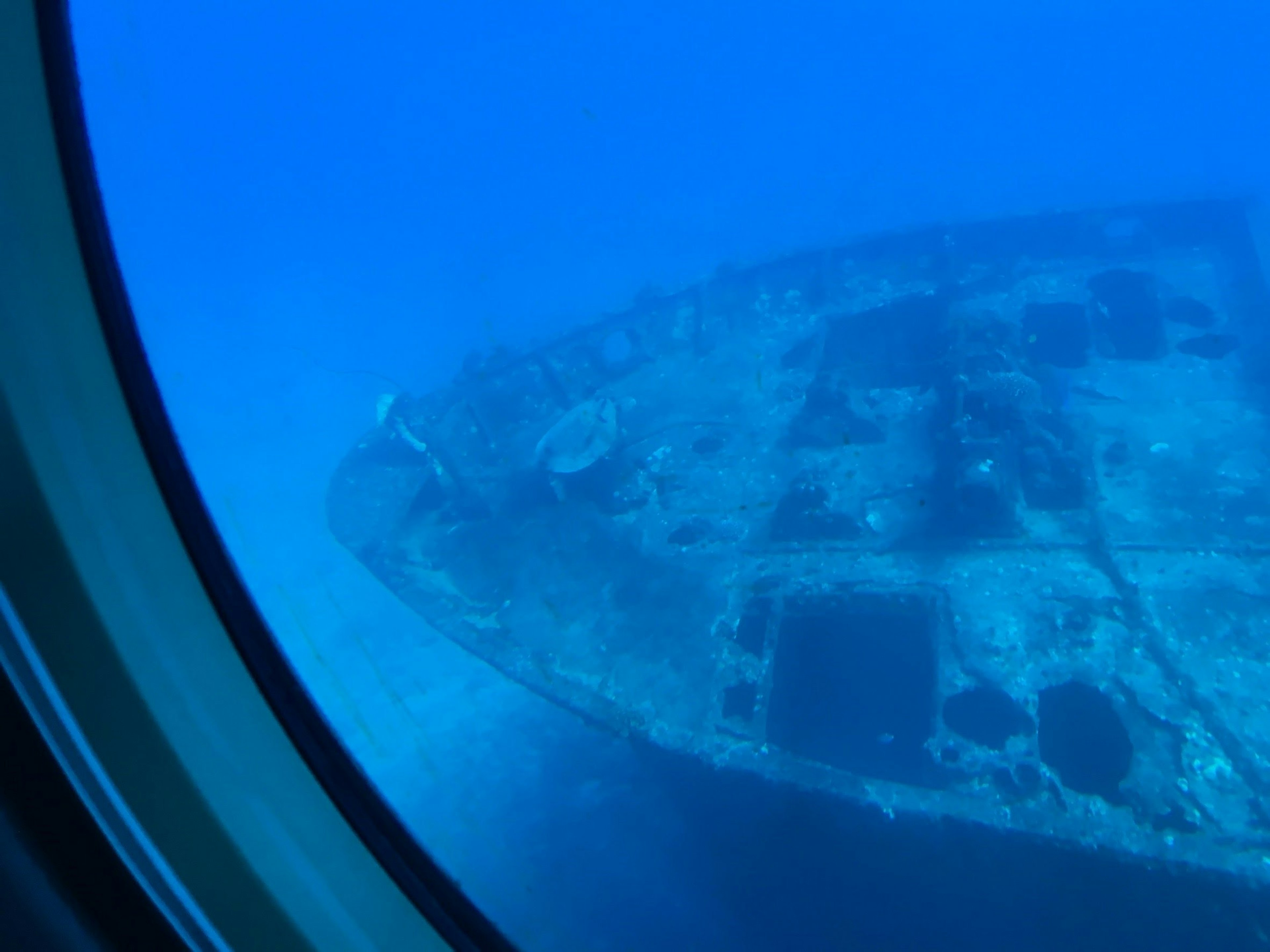 Wreck of a ship visible through a porthole underwater