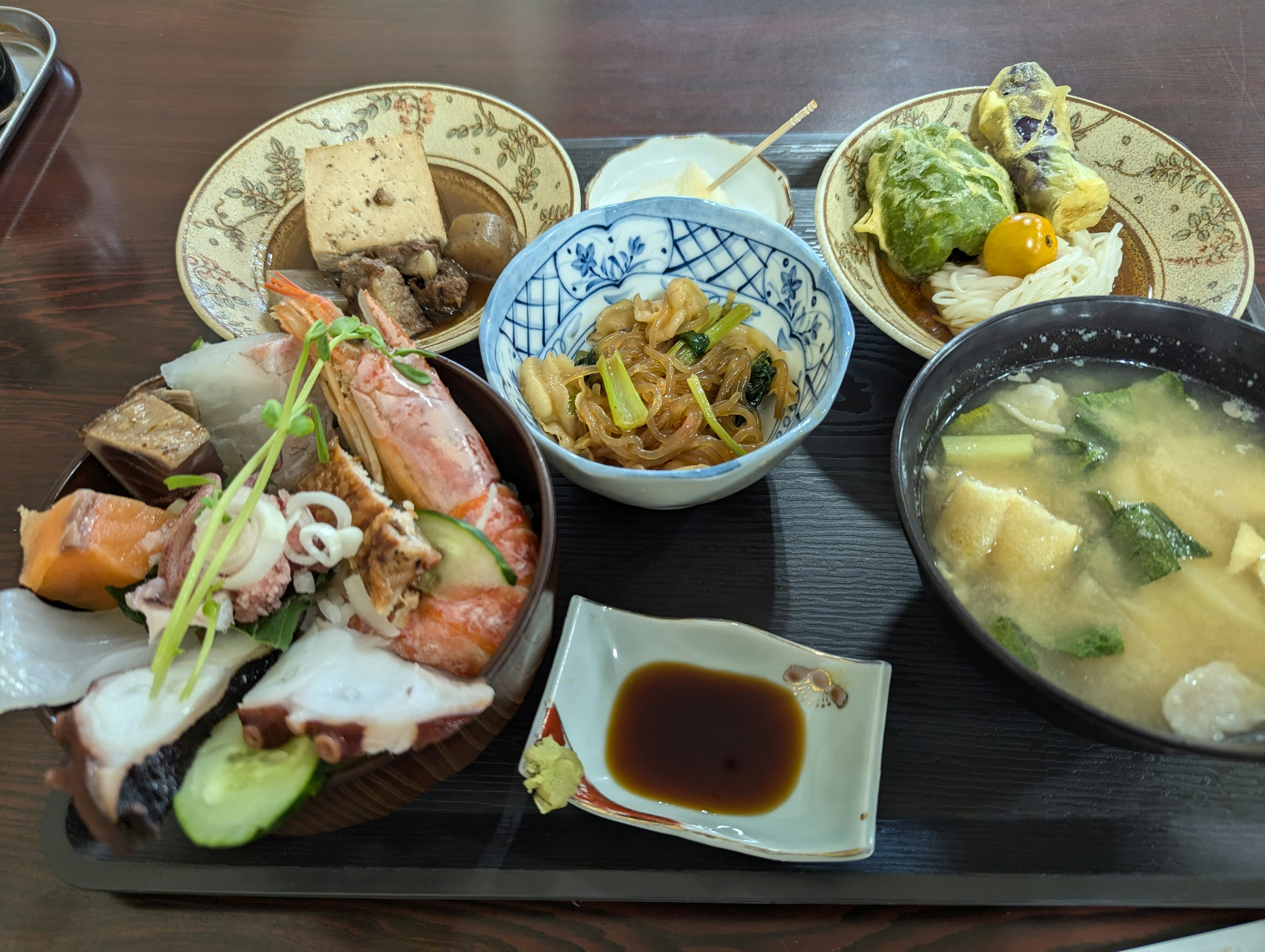 A Japanese meal featuring a seafood bowl and miso soup