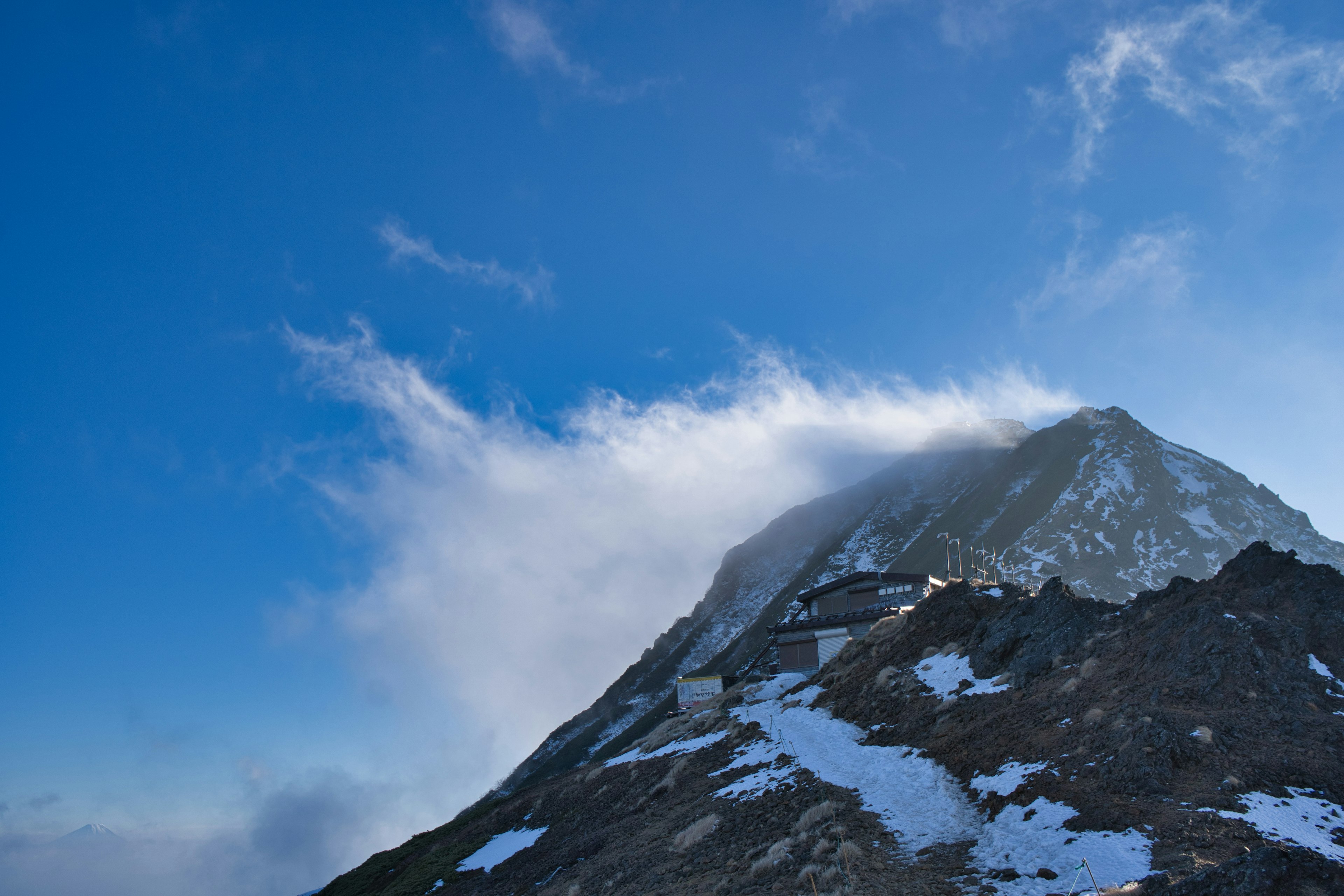 Picco di montagna coperto di neve contro un cielo blu brillante con nuvole