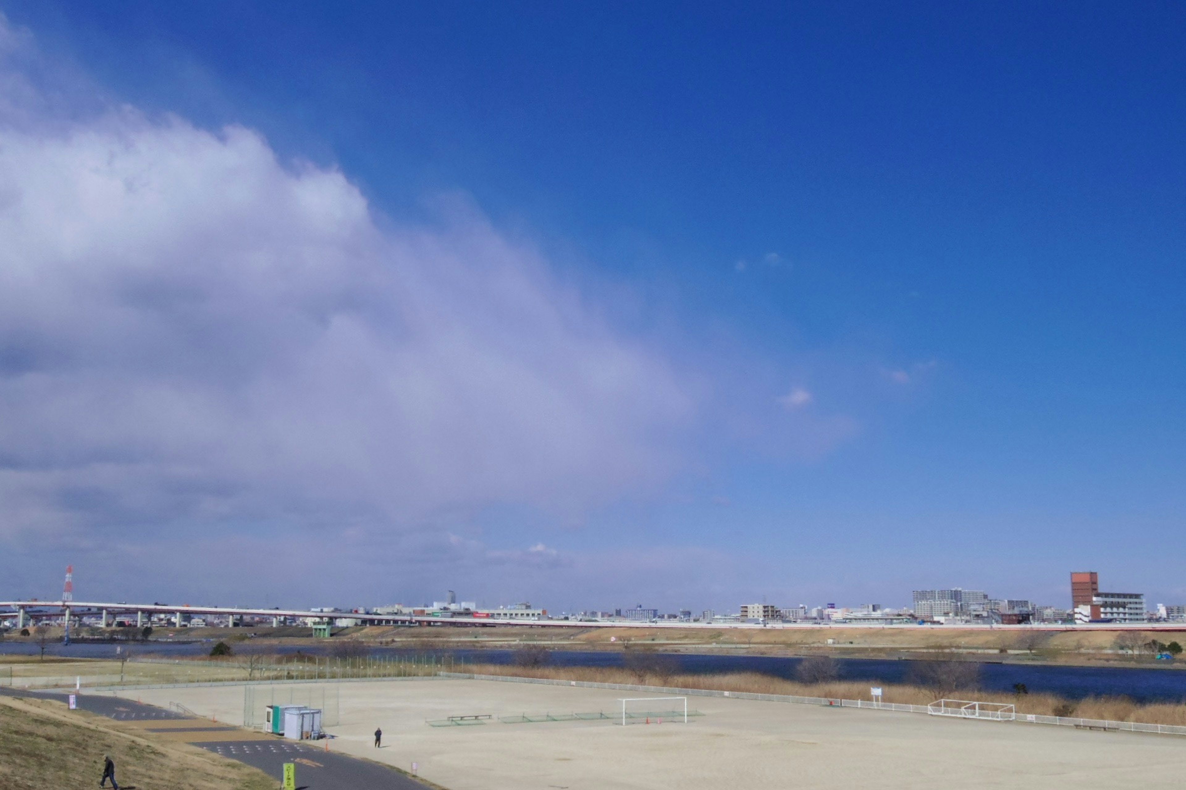 Un paysage avec un ciel bleu et des nuages comprenant une rivière et une berge