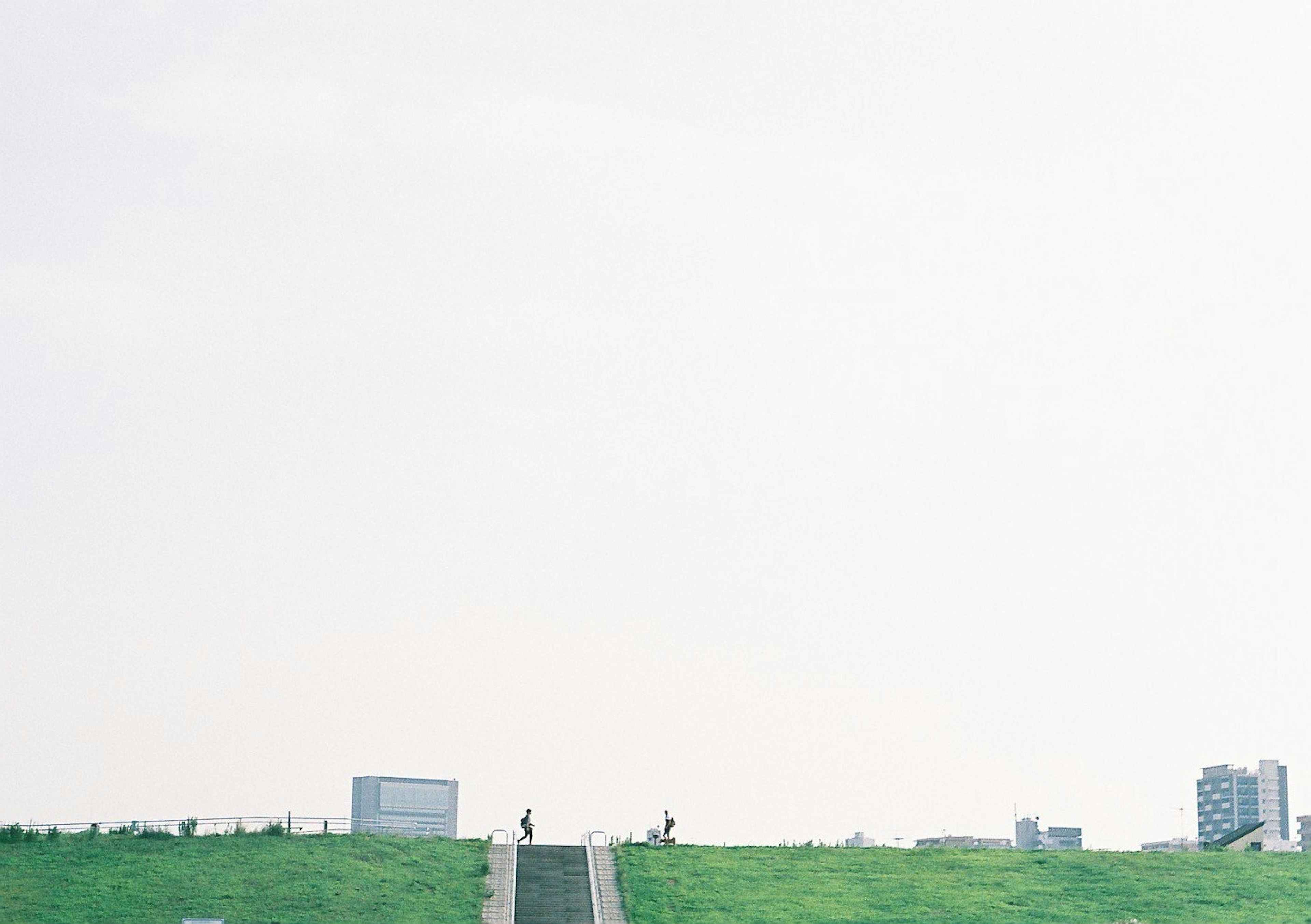 Wide green hill with distant buildings and a clear sky