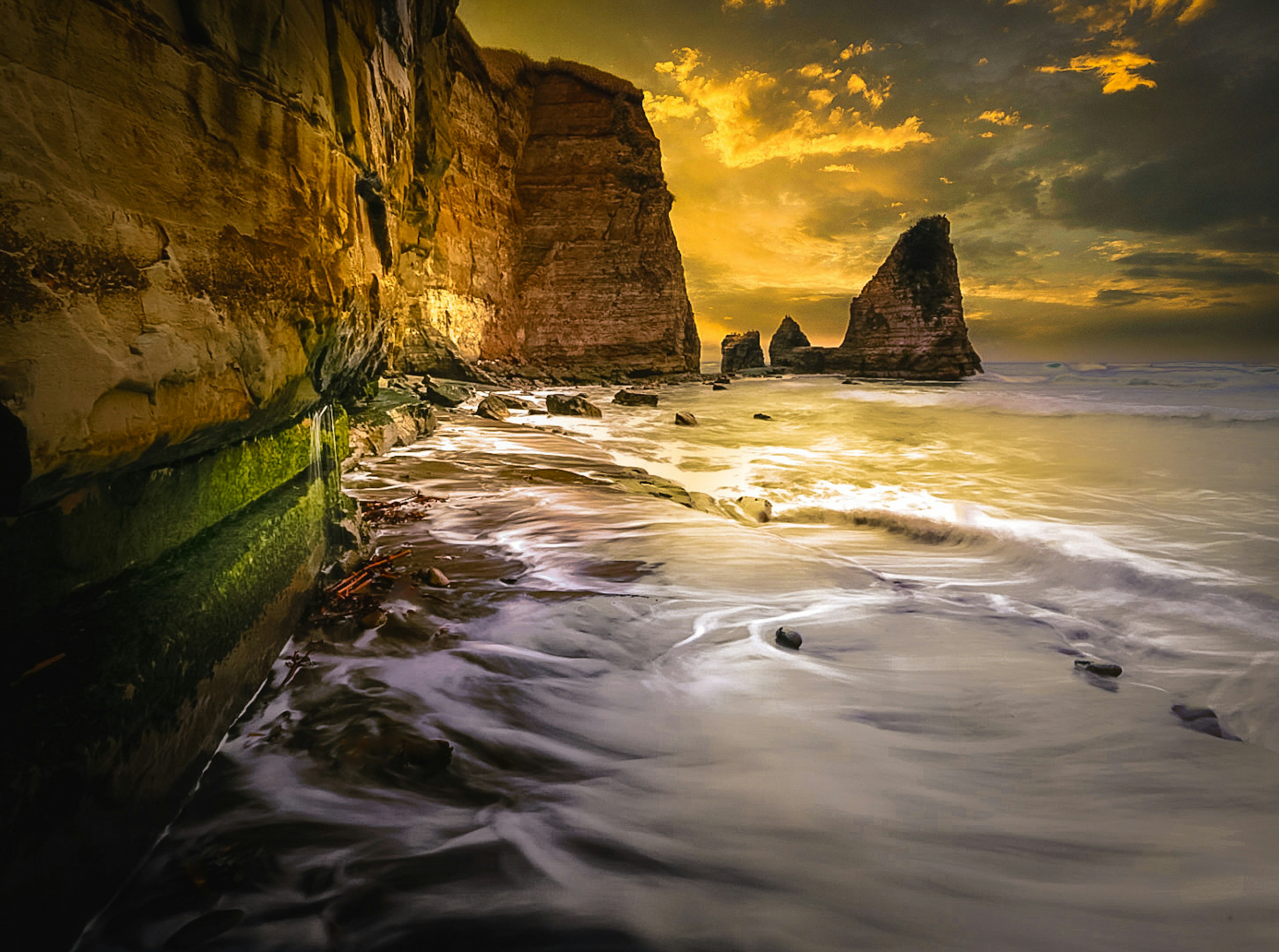 Beautiful coastal landscape with sunset sky rock formations gentle waves green moss