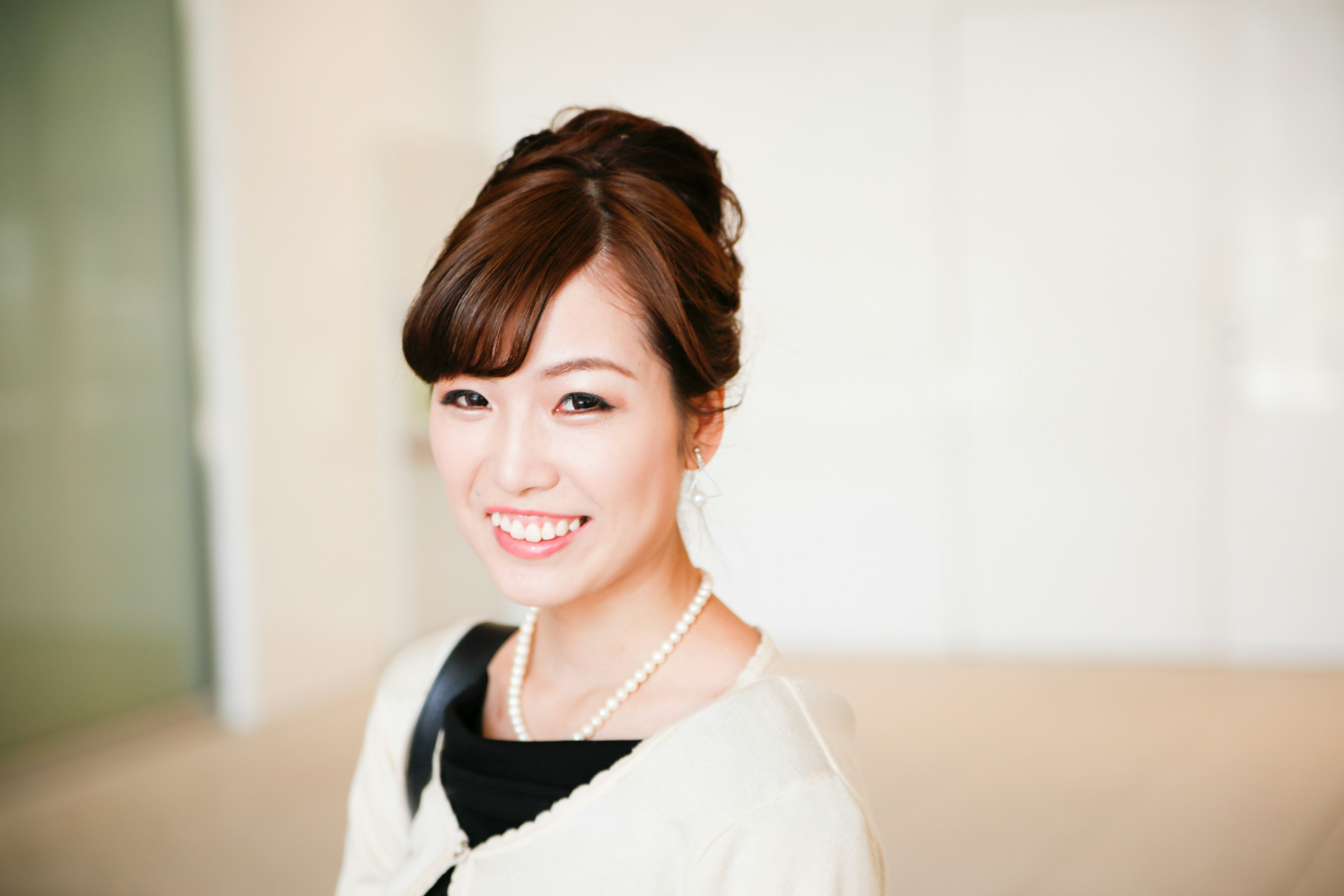 Portrait of a smiling woman with a bright background and elegant attire