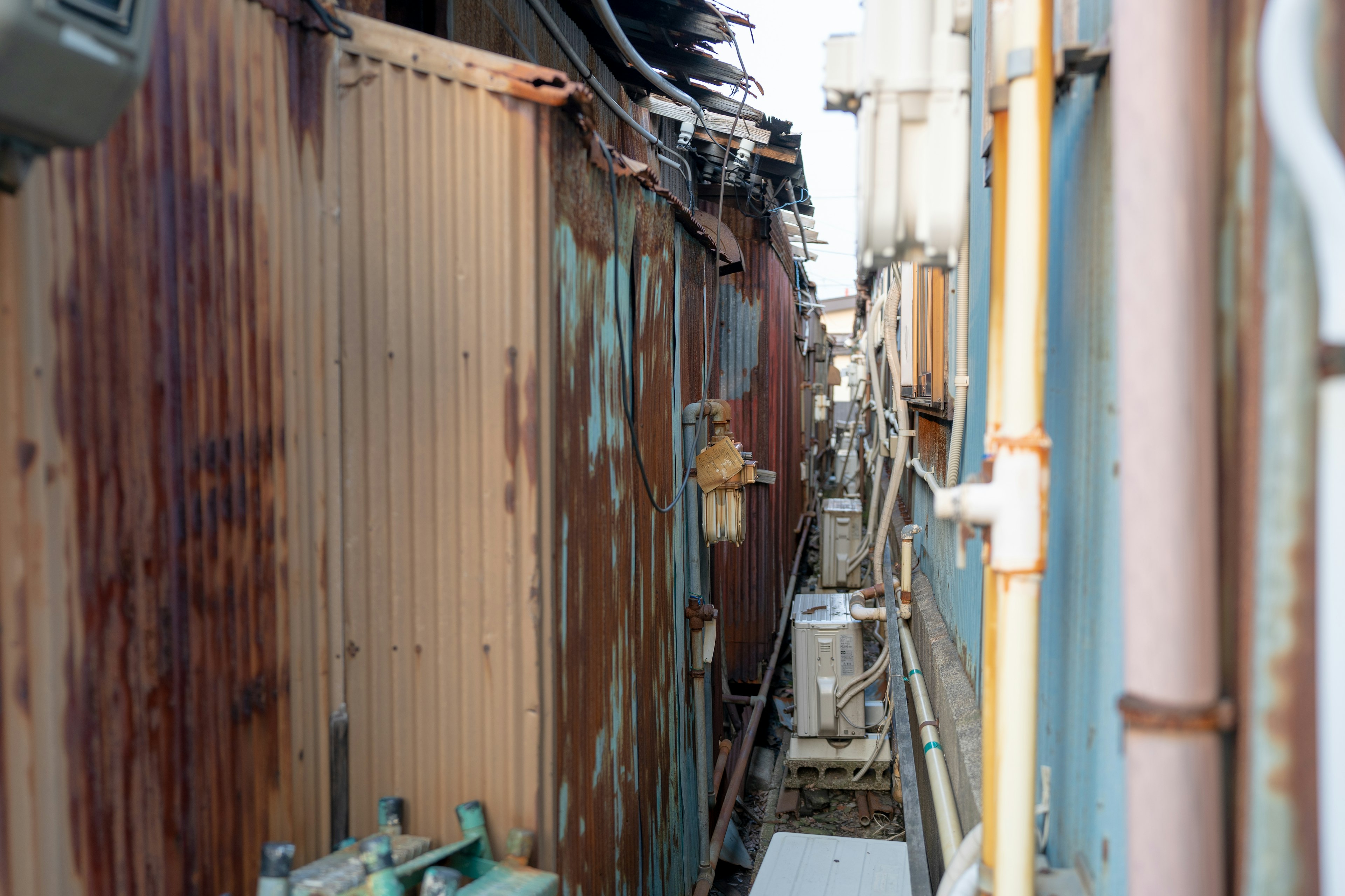 Schmale Gasse mit alten Metallwänden und Rohren