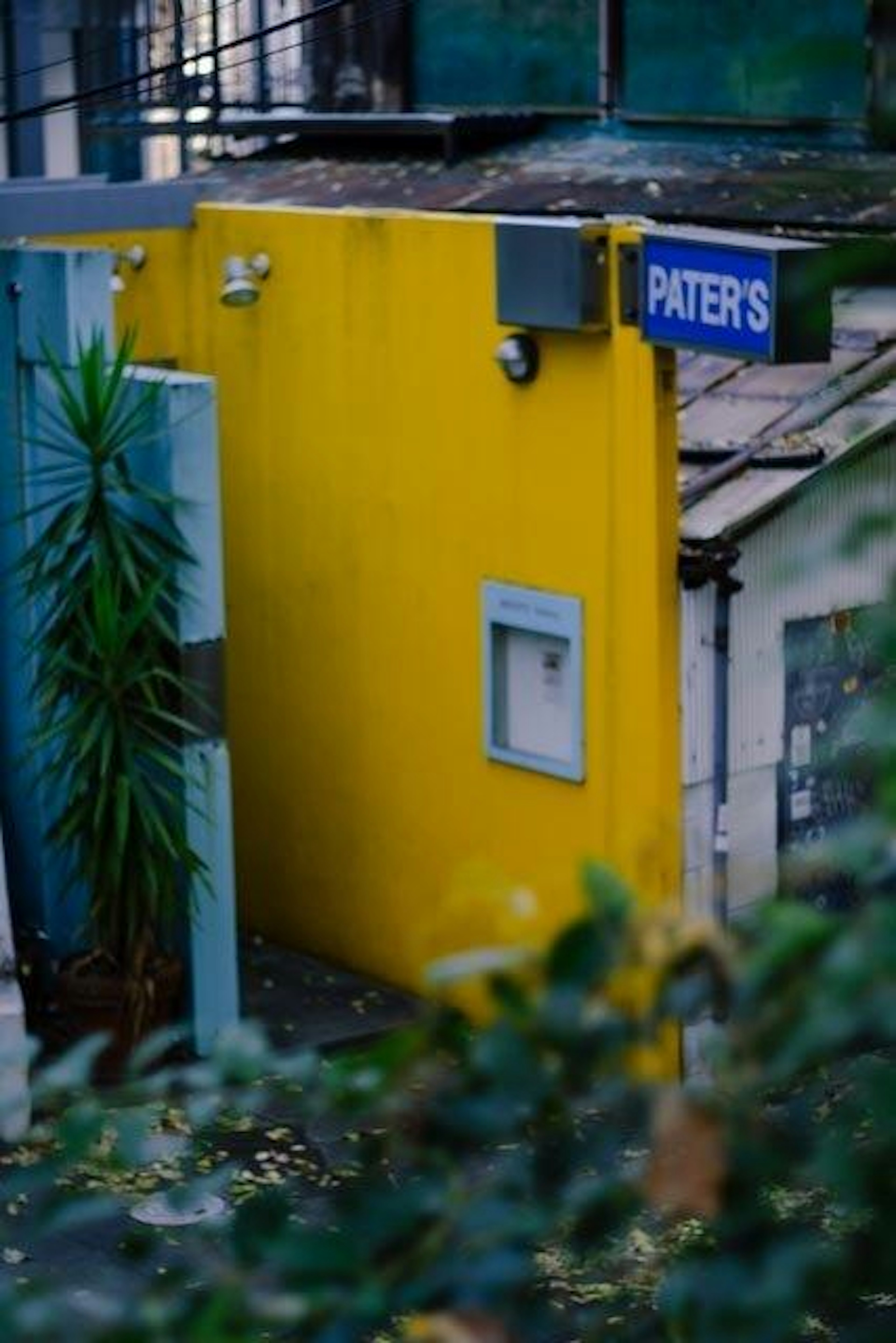 Entrance of a building with a yellow wall and a blue sign