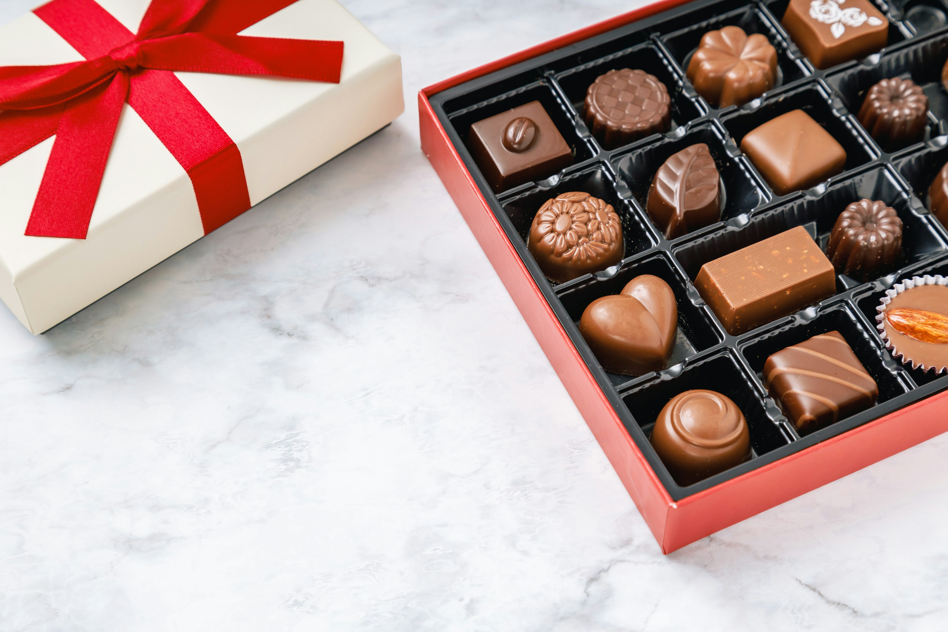 White gift box with red ribbon and assorted chocolates inside