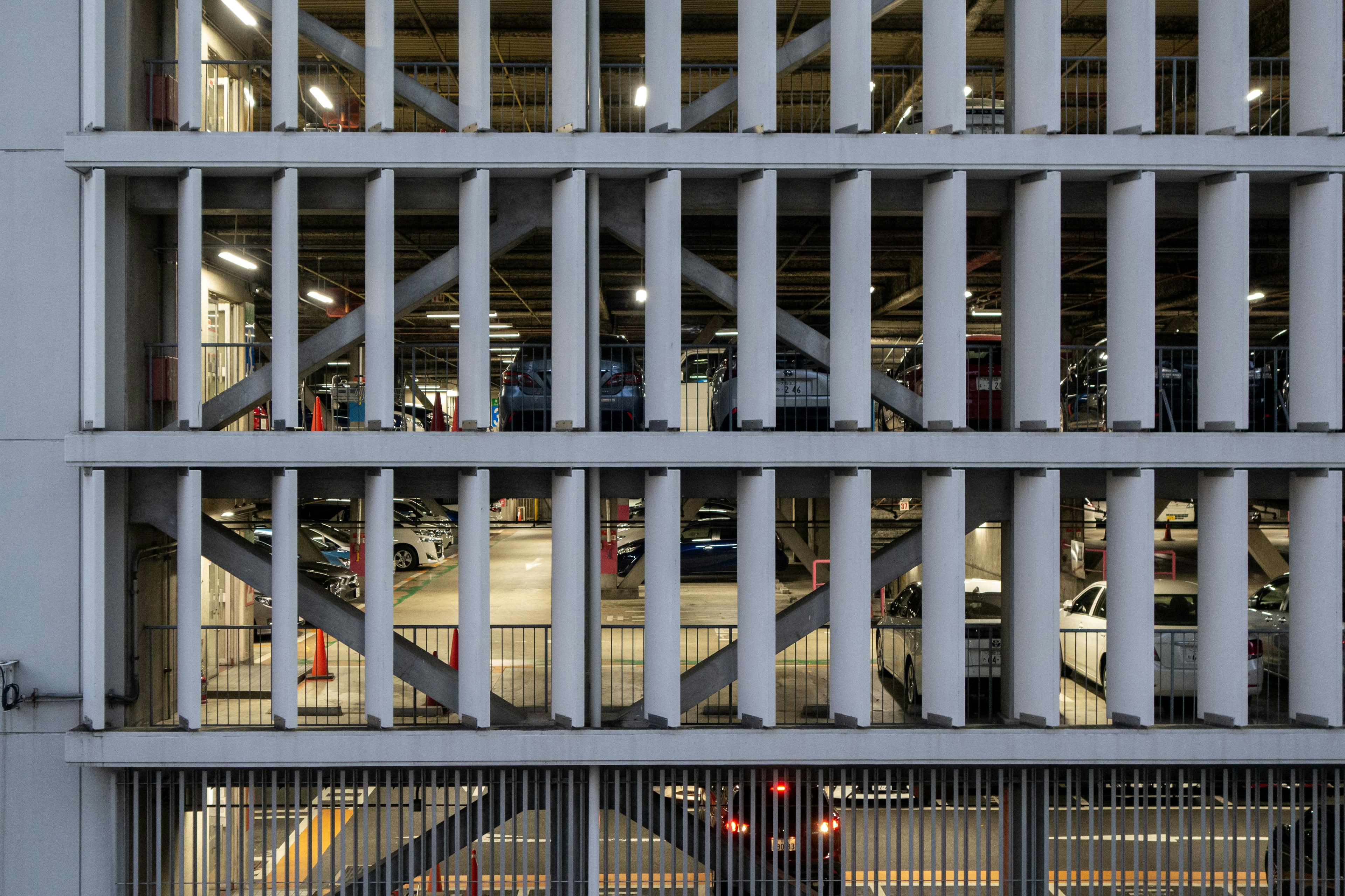 Imagen de una estructura de estacionamiento con ranuras verticales y coches visibles