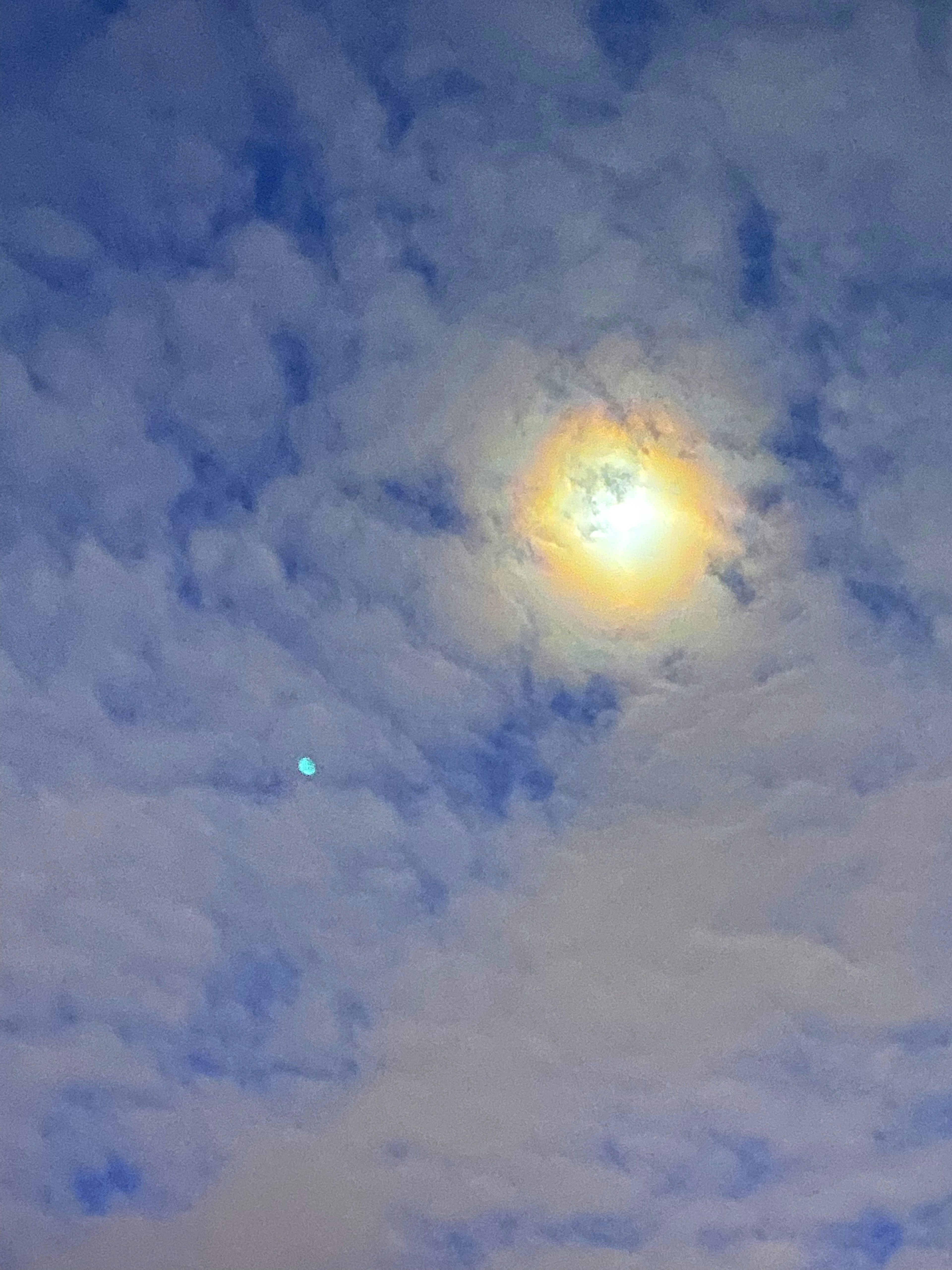 Heller Sonnenstrahl umgeben von Wolken in einem blauen Himmel