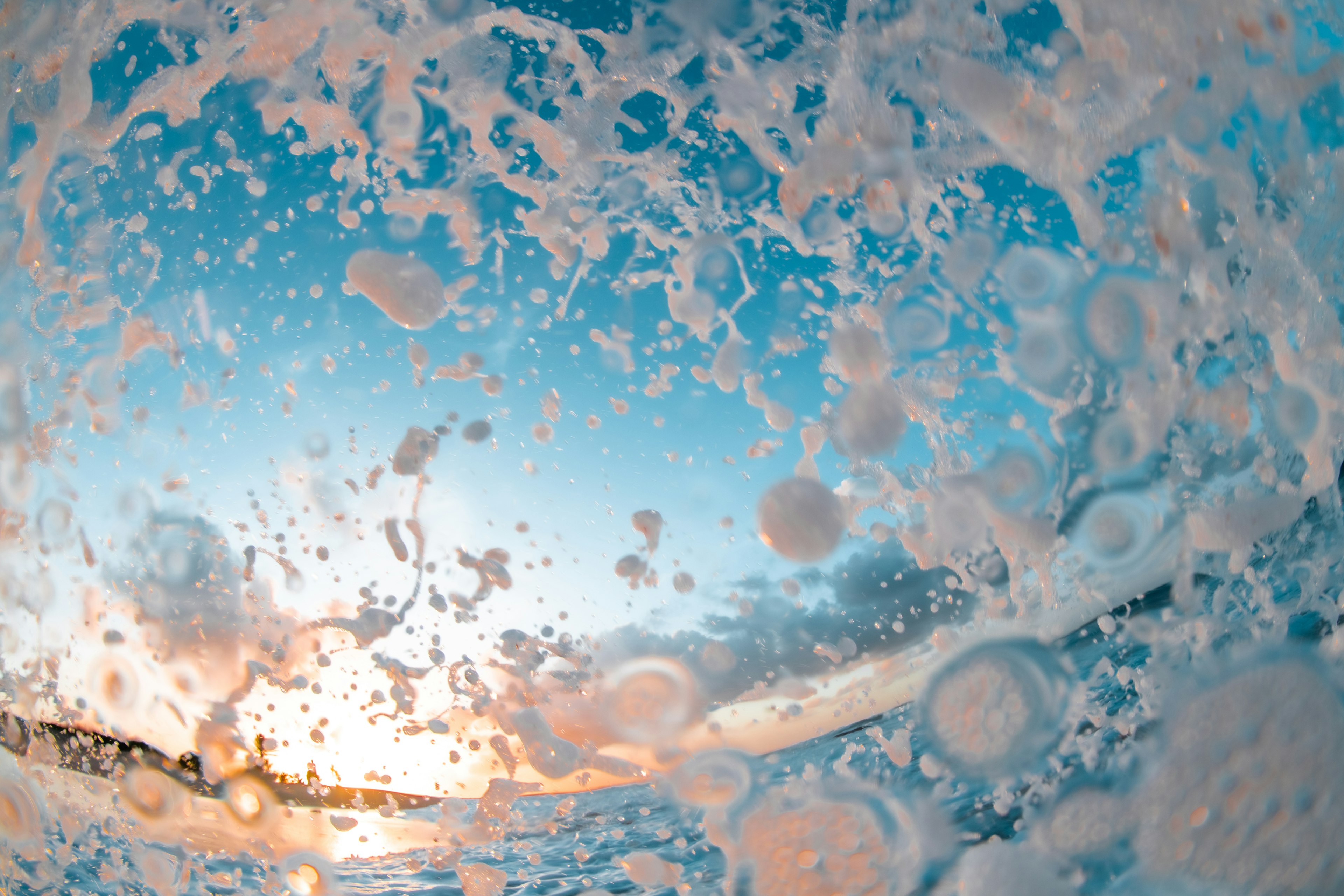 波の泡と青い空の夕日が見える海の写真