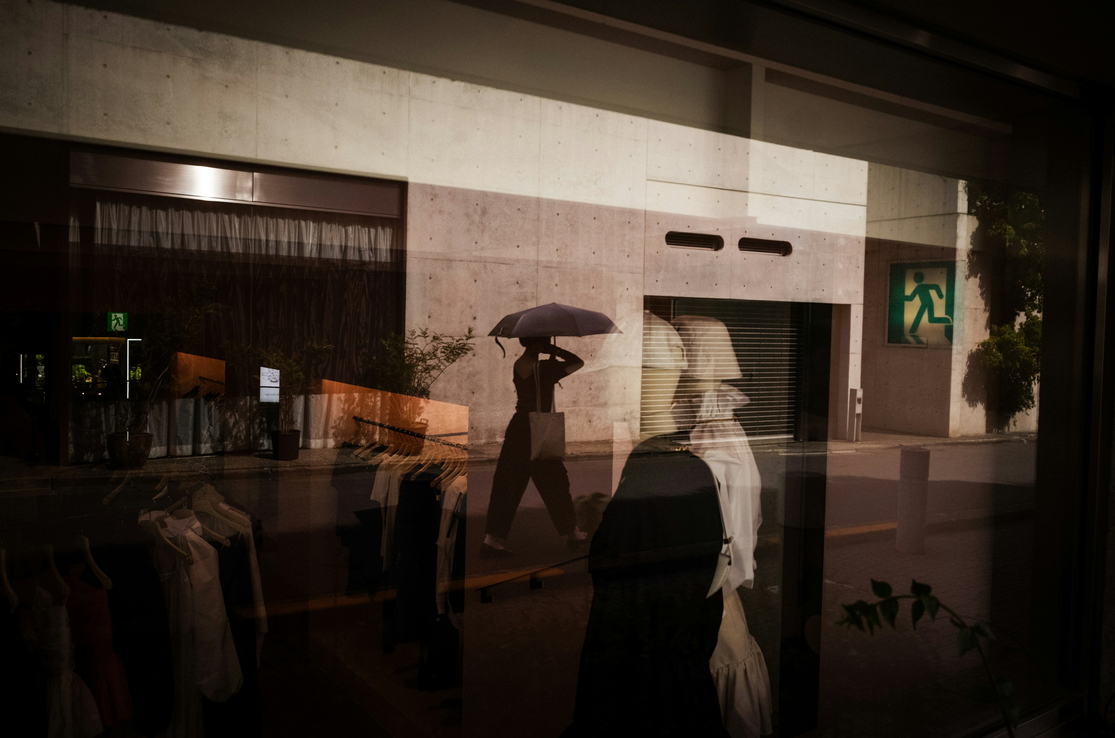 Street scene with a person holding an umbrella reflected in a window