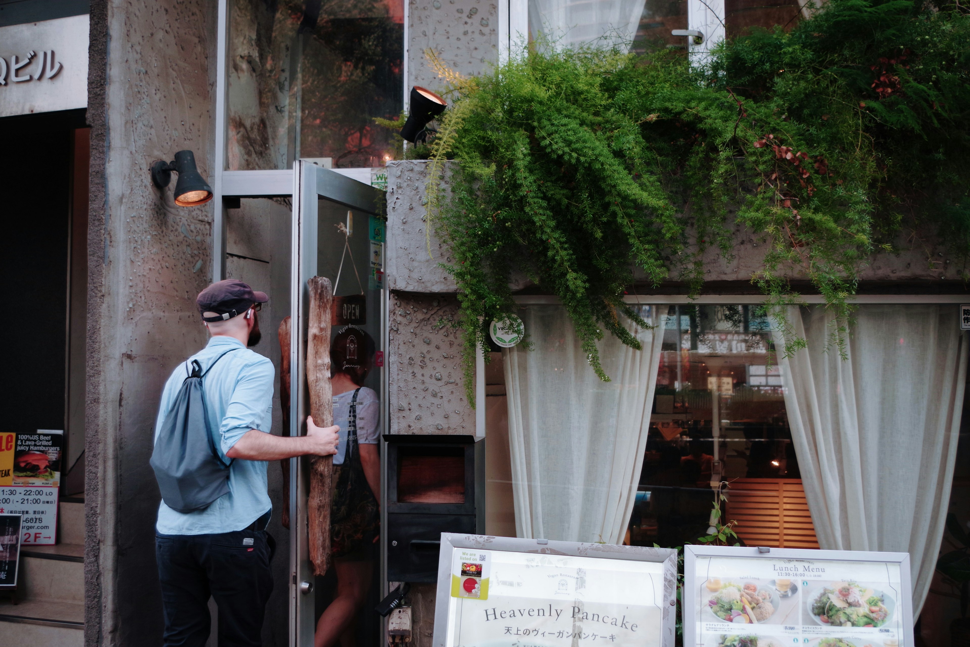 Man opening the door of a cafe adorned with plants