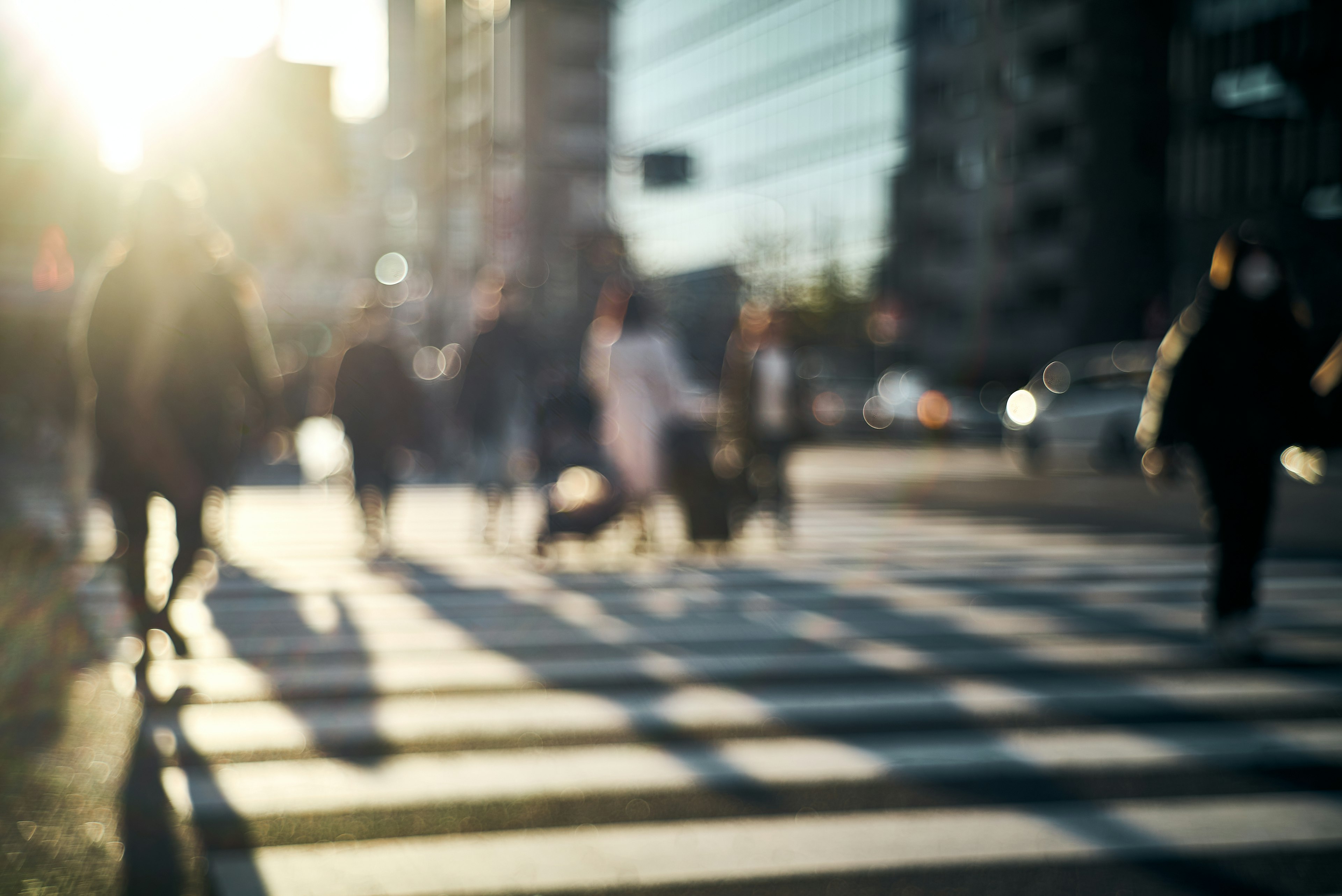 Verschwommene Szene von Menschen, die eine Straße mit Schatten auf dem Zebrastreifen überqueren