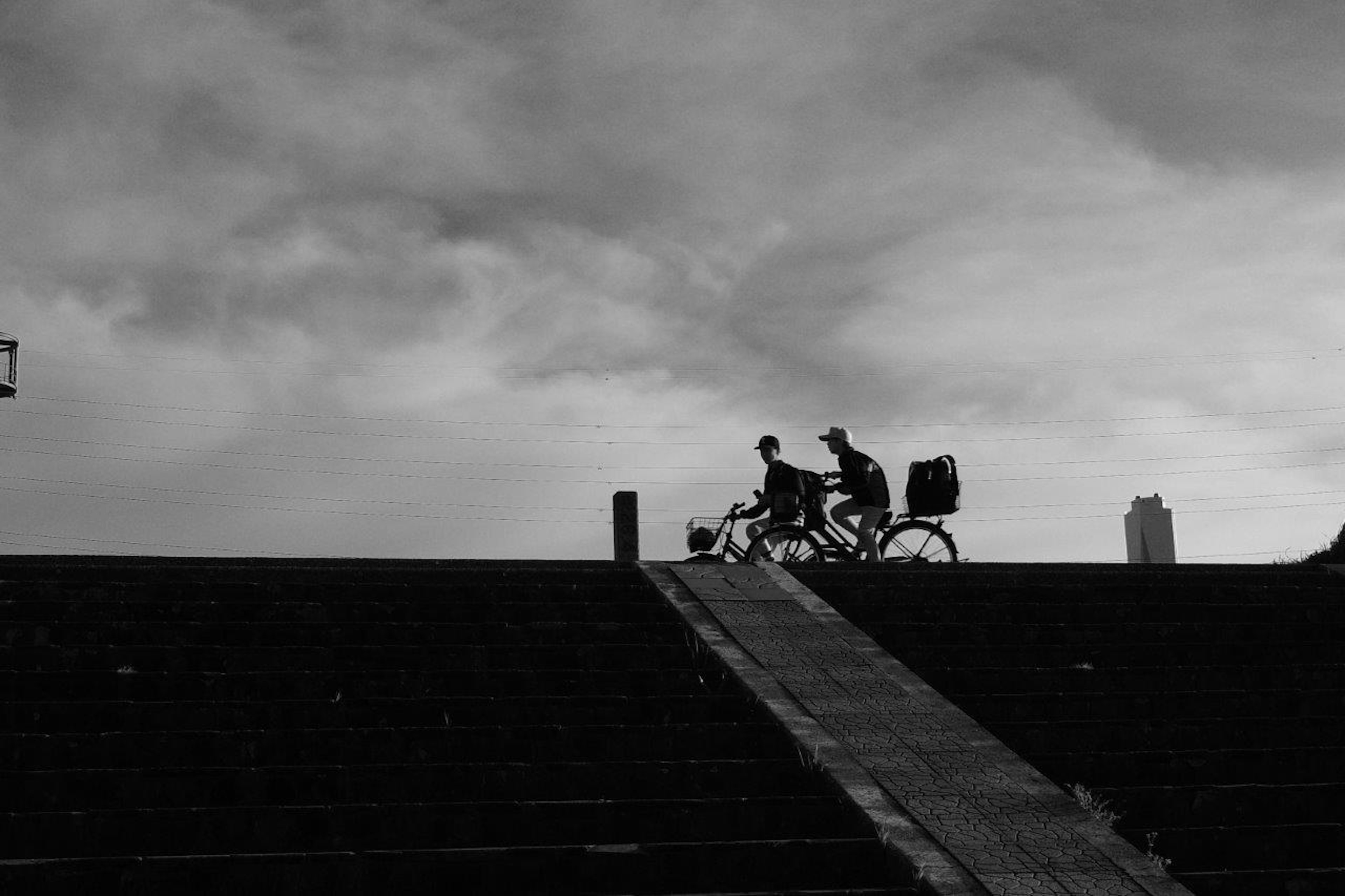 Dos personas montando en bicicleta bajando una rampa en una foto en blanco y negro