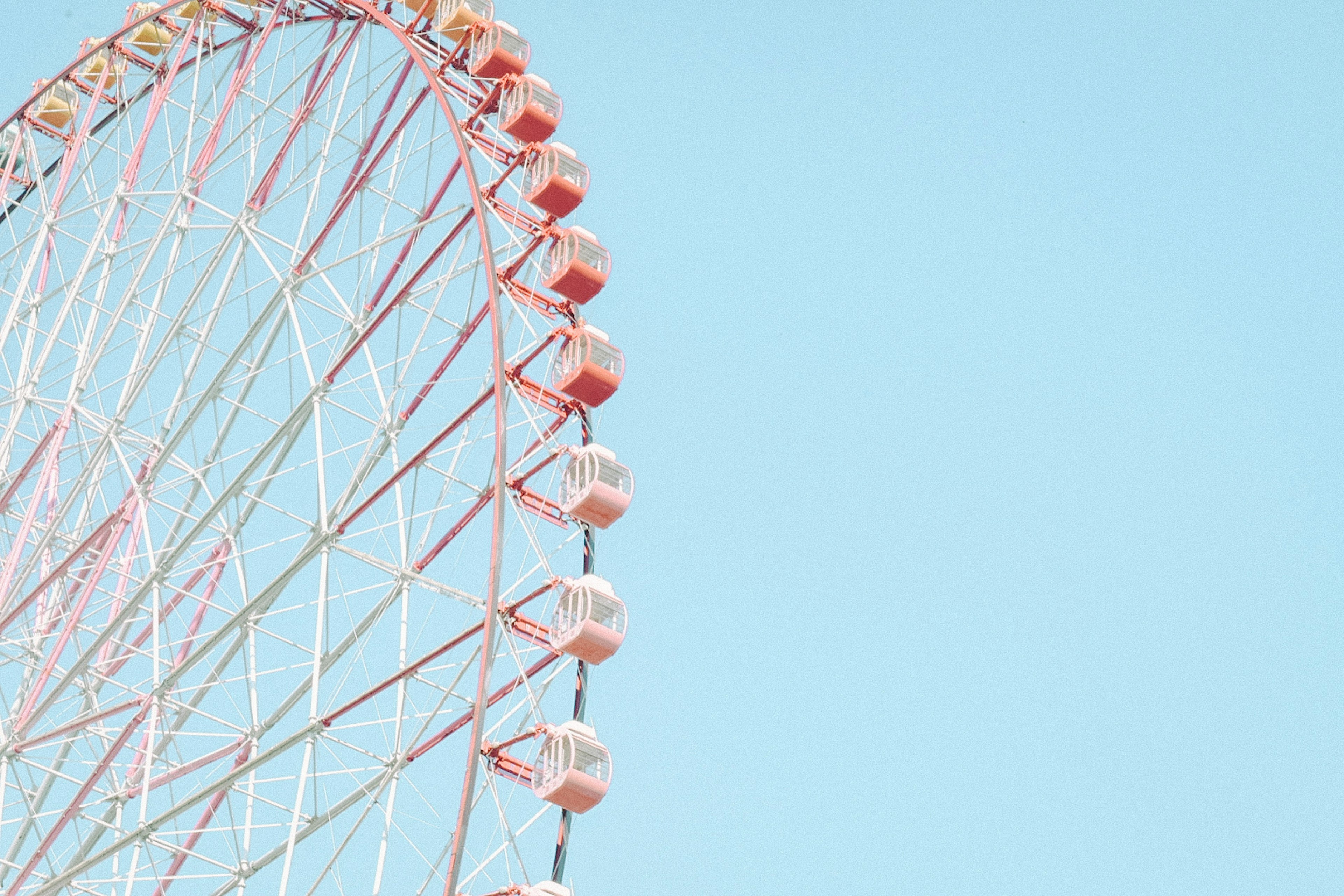 Partial view of a ferris wheel under a blue sky colorful gondolas arranged