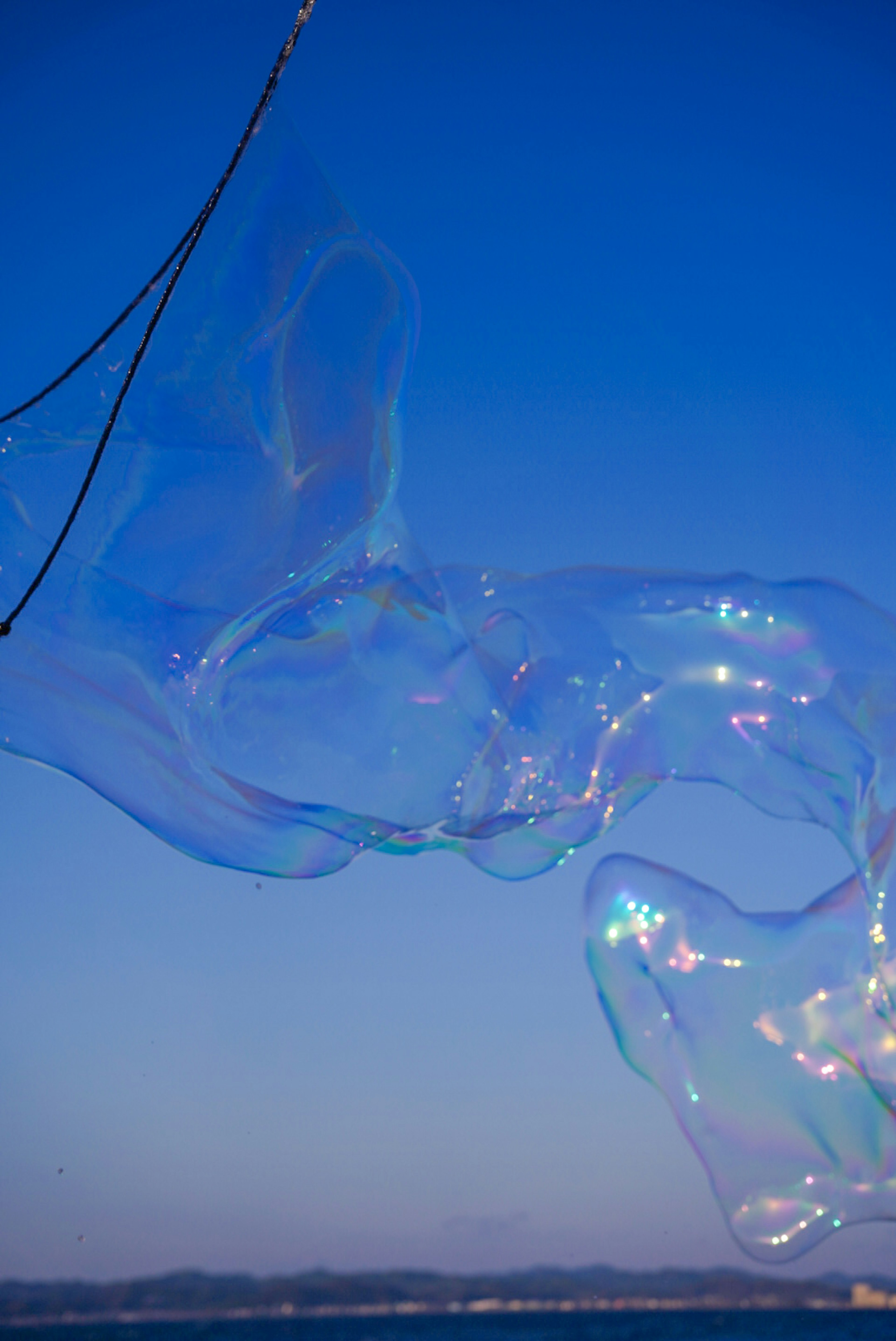 Eine große Seifenblase schwebt unter einem blauen Himmel