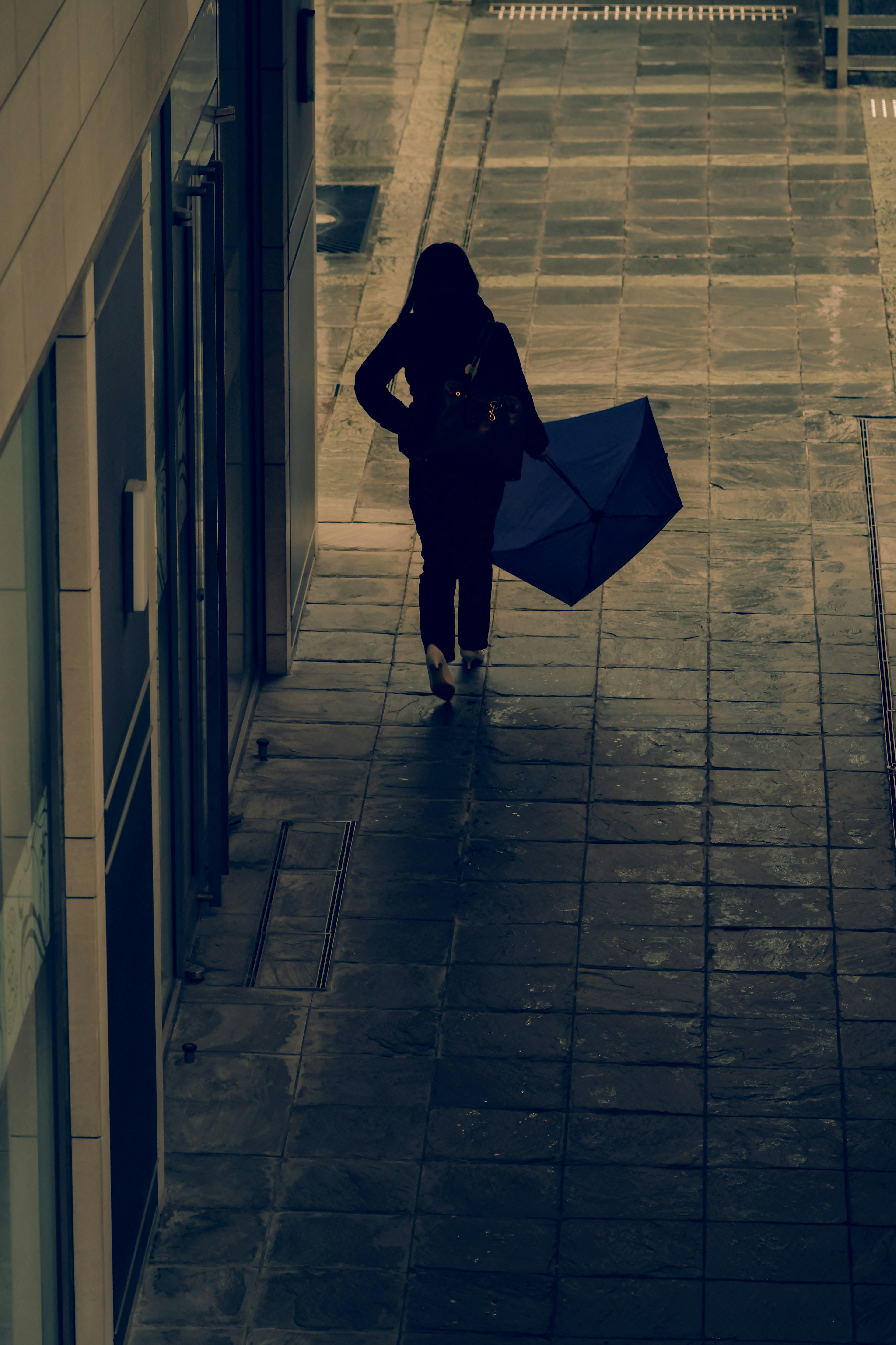 Silhouette of a person walking with an umbrella in the rain