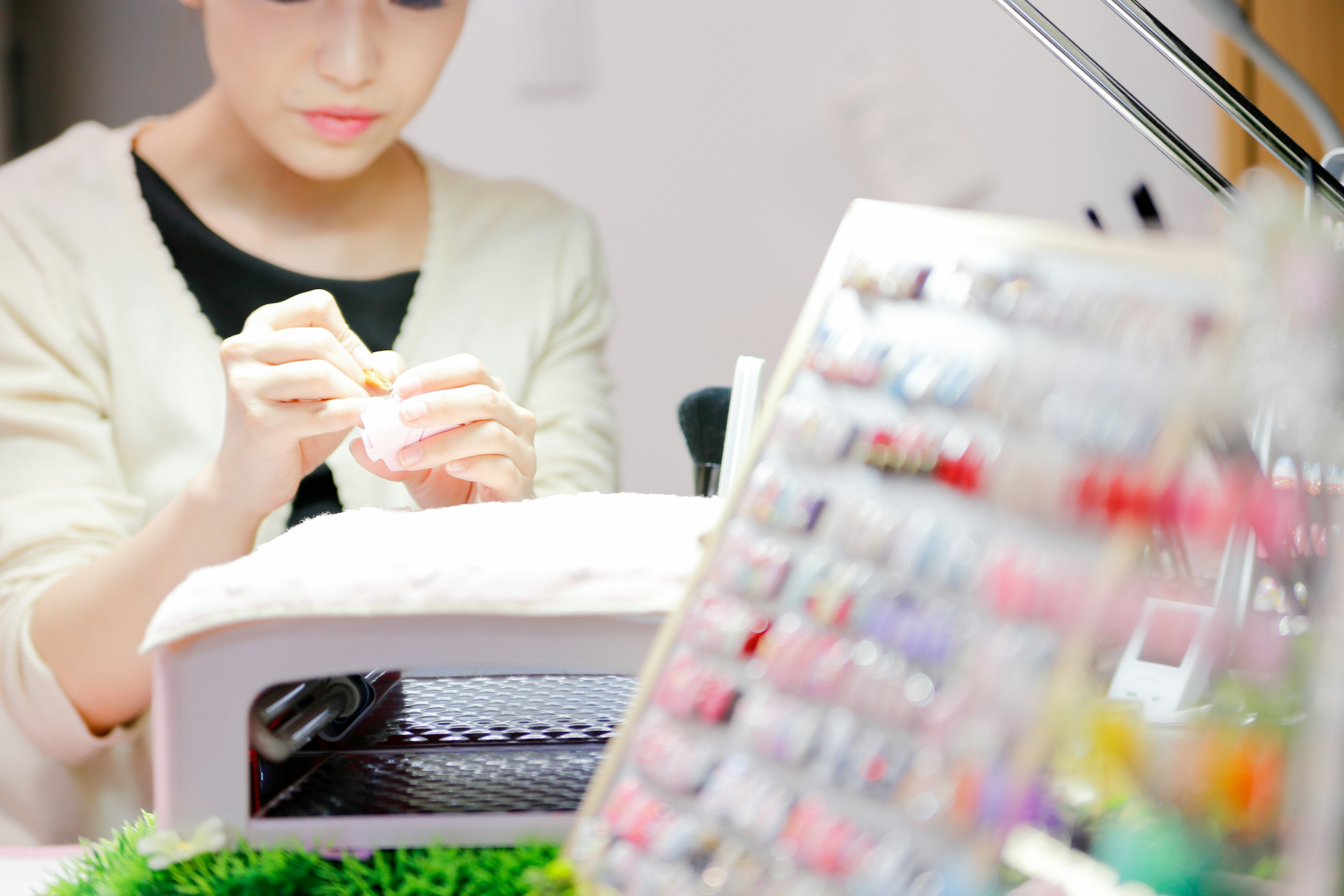 Mujer concentrada en el arte de las uñas en un salón con una variedad de esmaltes