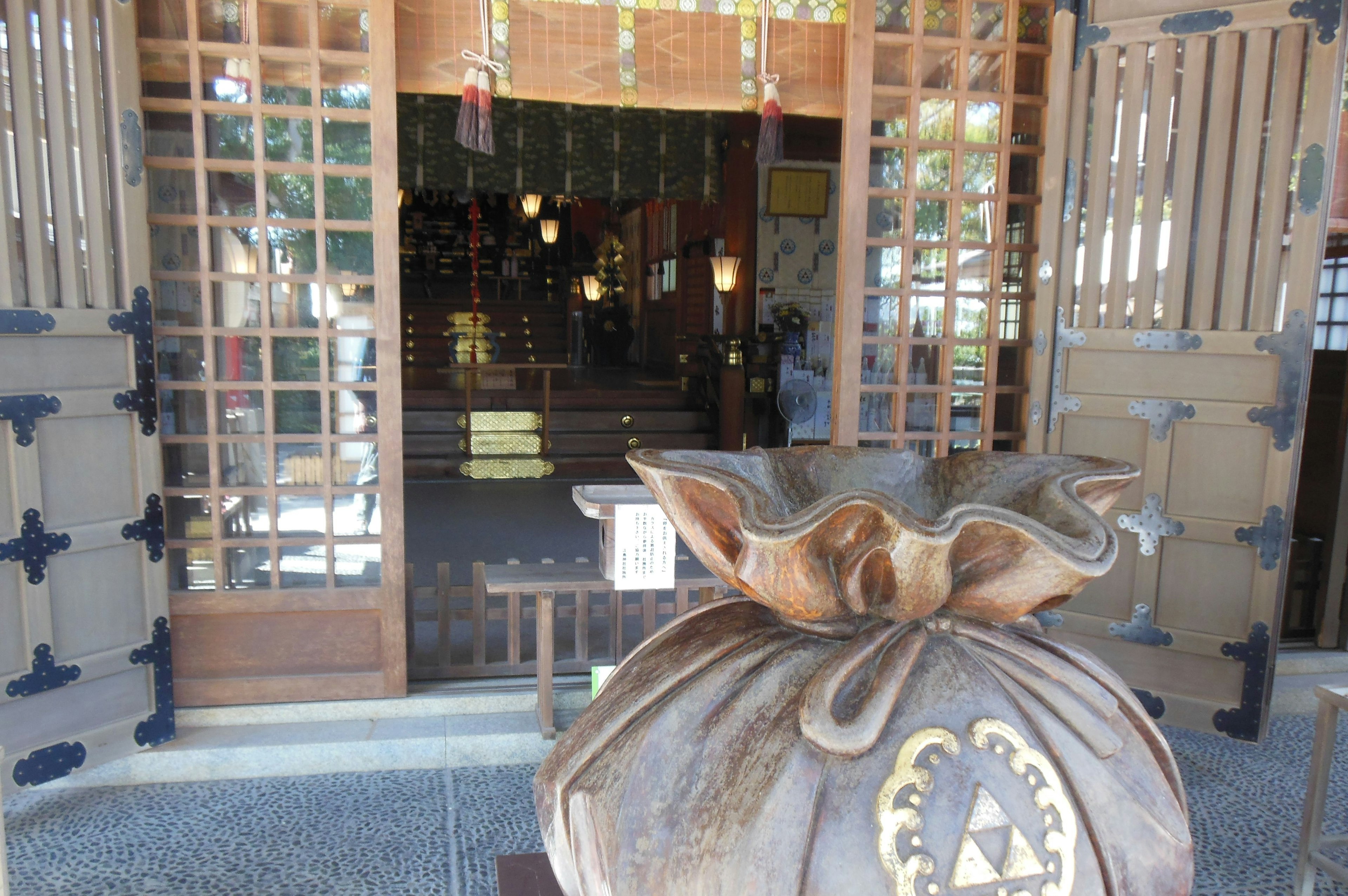 Kantong kayu besar di pintu masuk dengan pintu bangunan Jepang tradisional di latar belakang