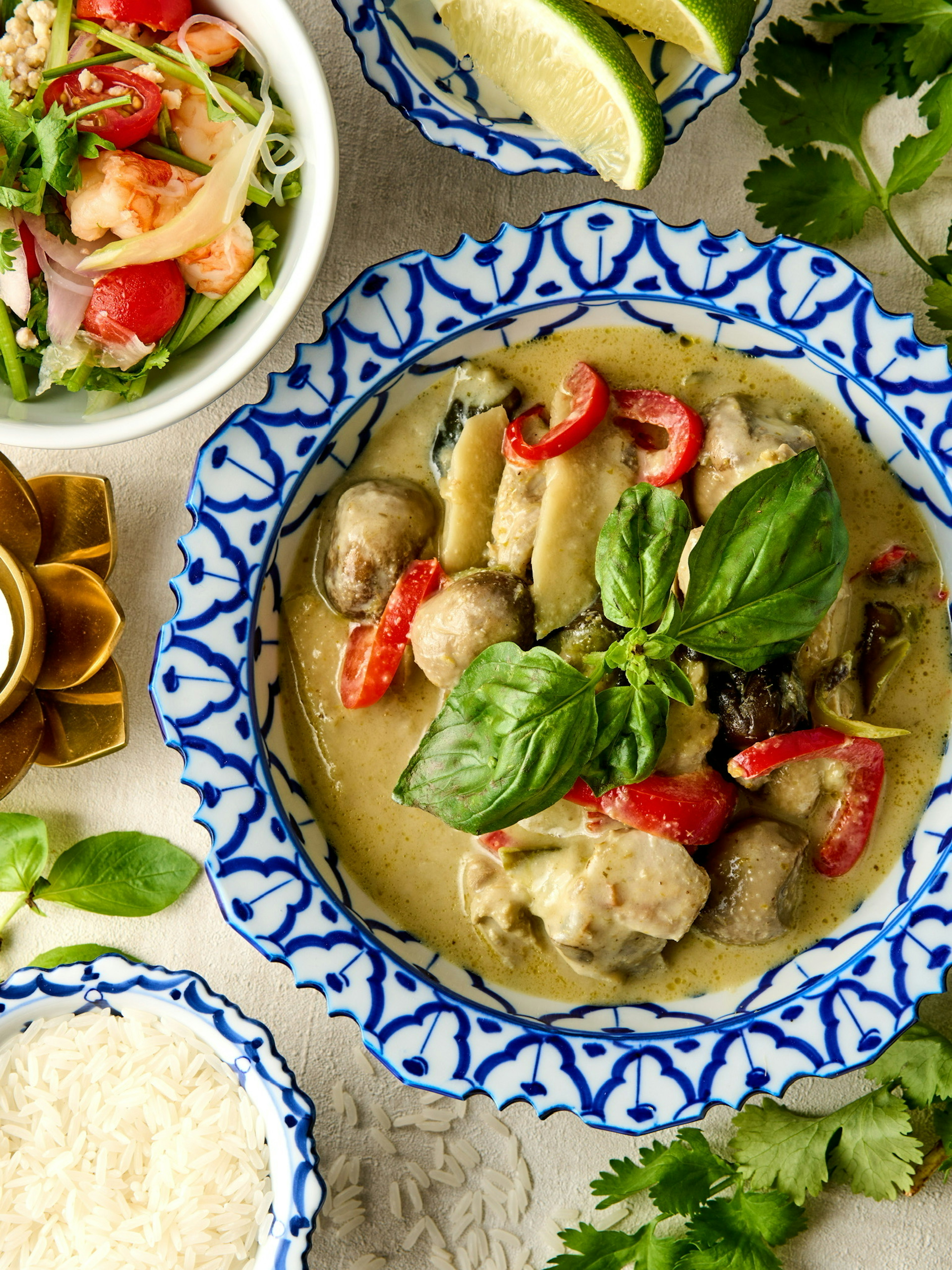 A vibrant bowl of green curry with fresh vegetables and herbs garnished on a decorative plate