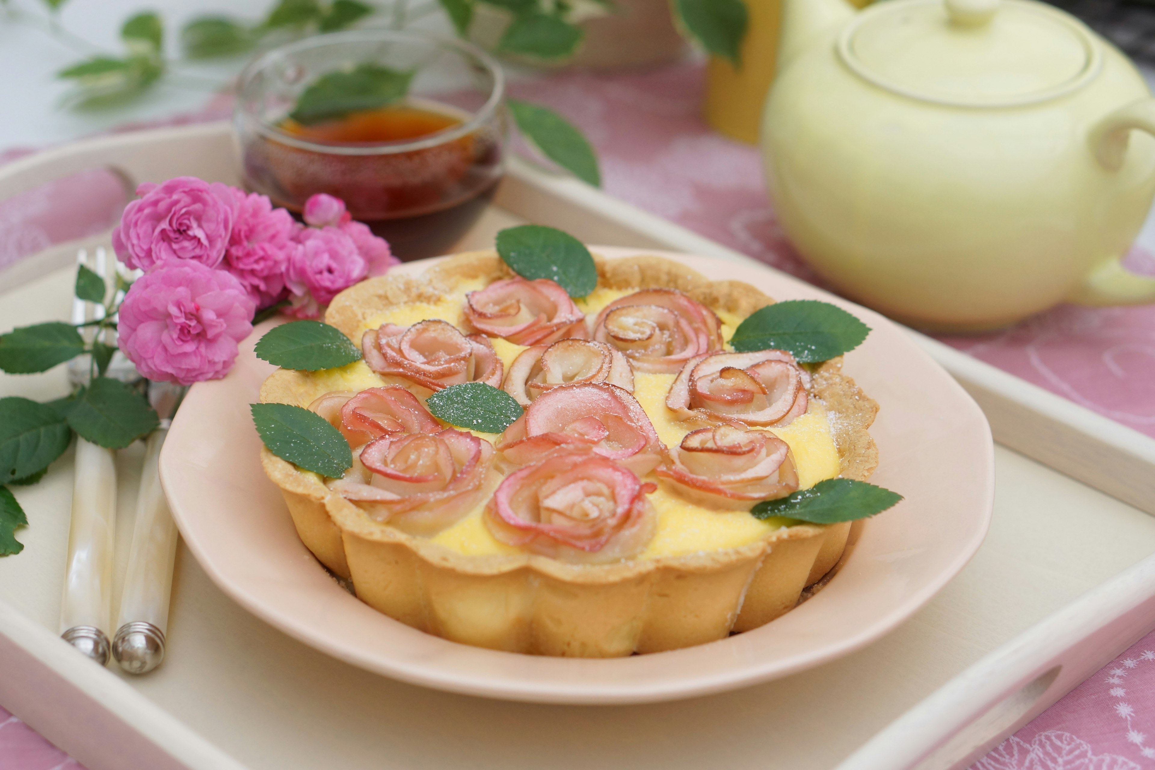 Beautiful tart decorated with rose designs and pink flowers on a table setting