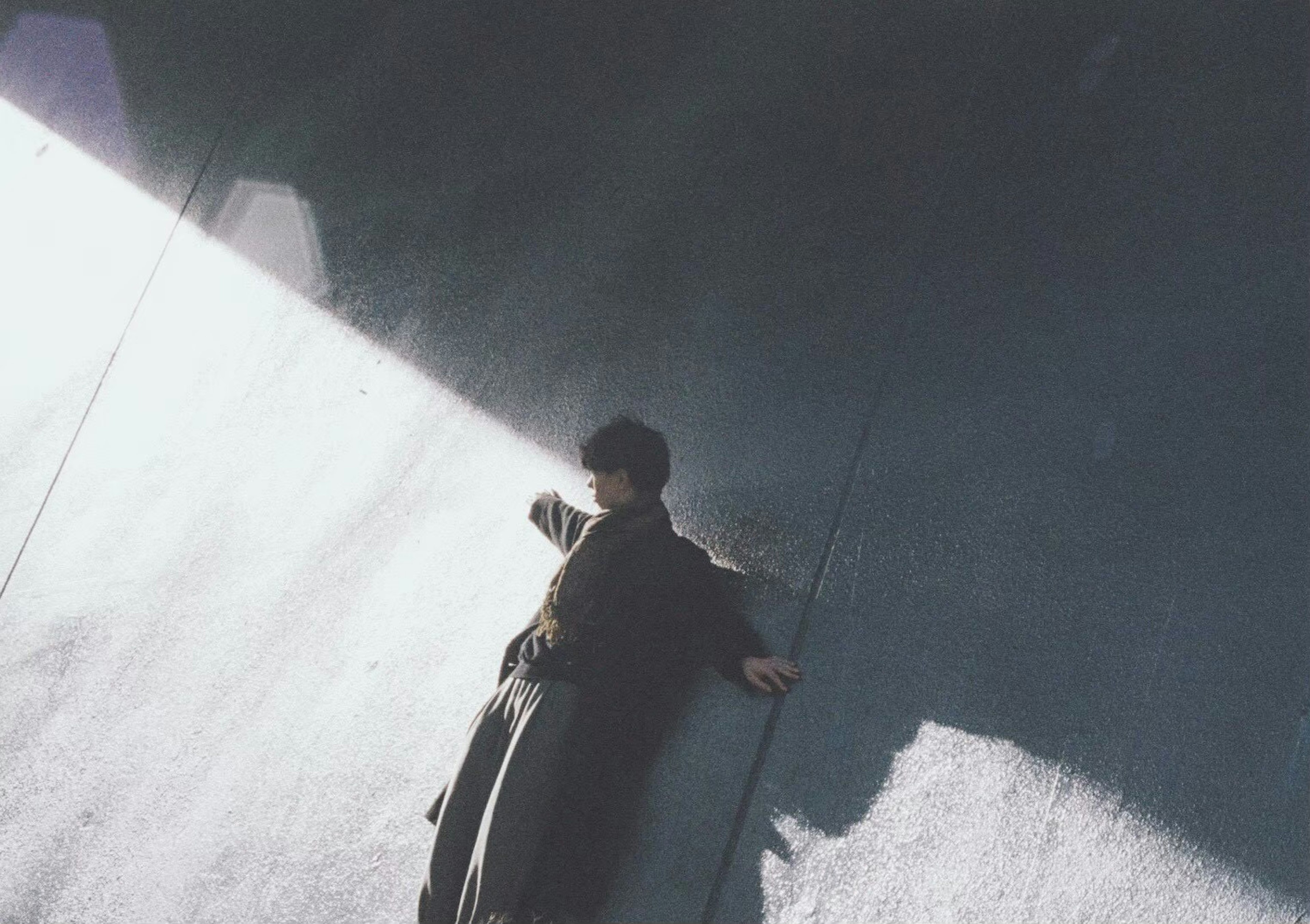 Person leaning against a wall with contrasting light