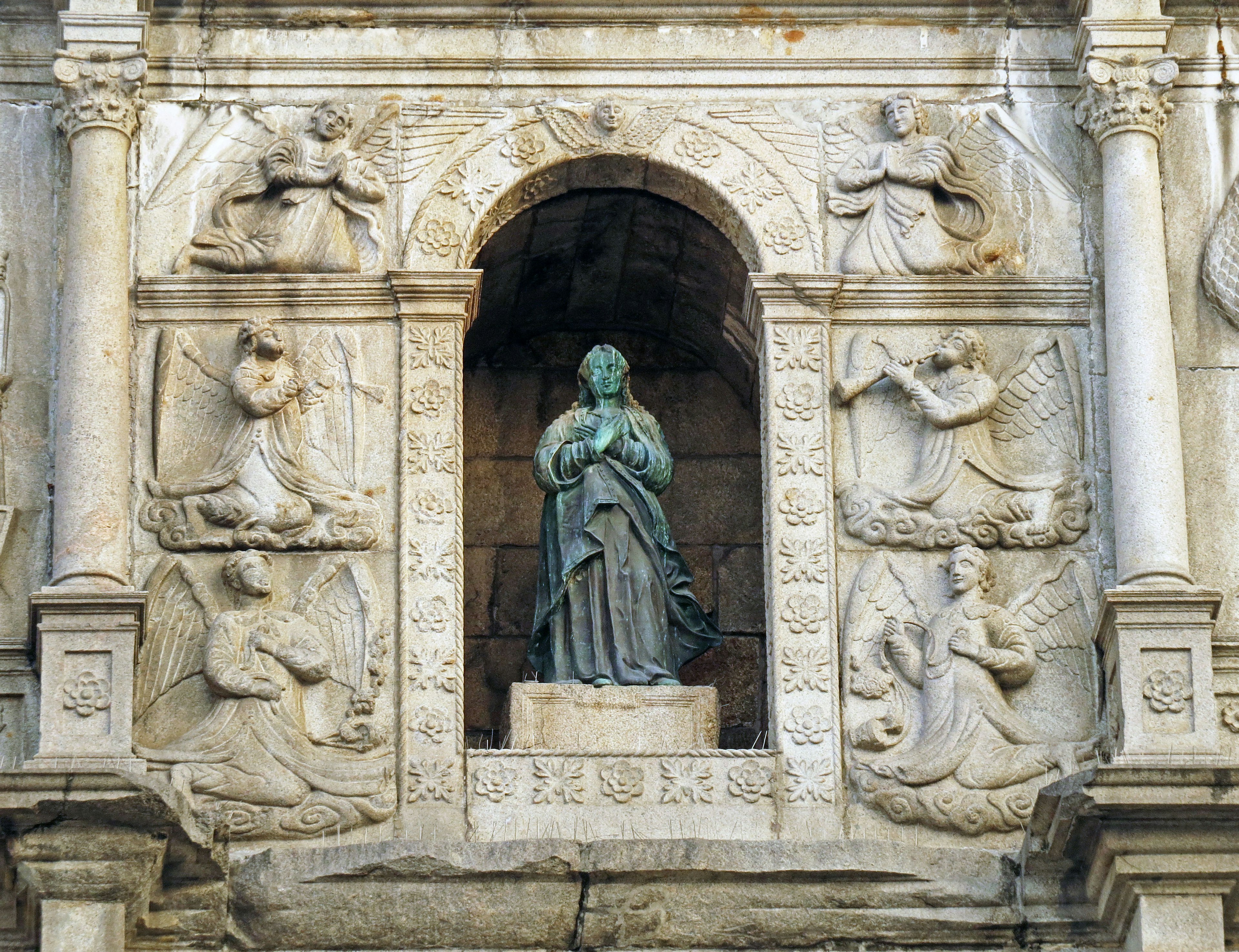 Statue der Jungfrau Maria in einer Steinfassade mit kunstvollen Schnitzereien