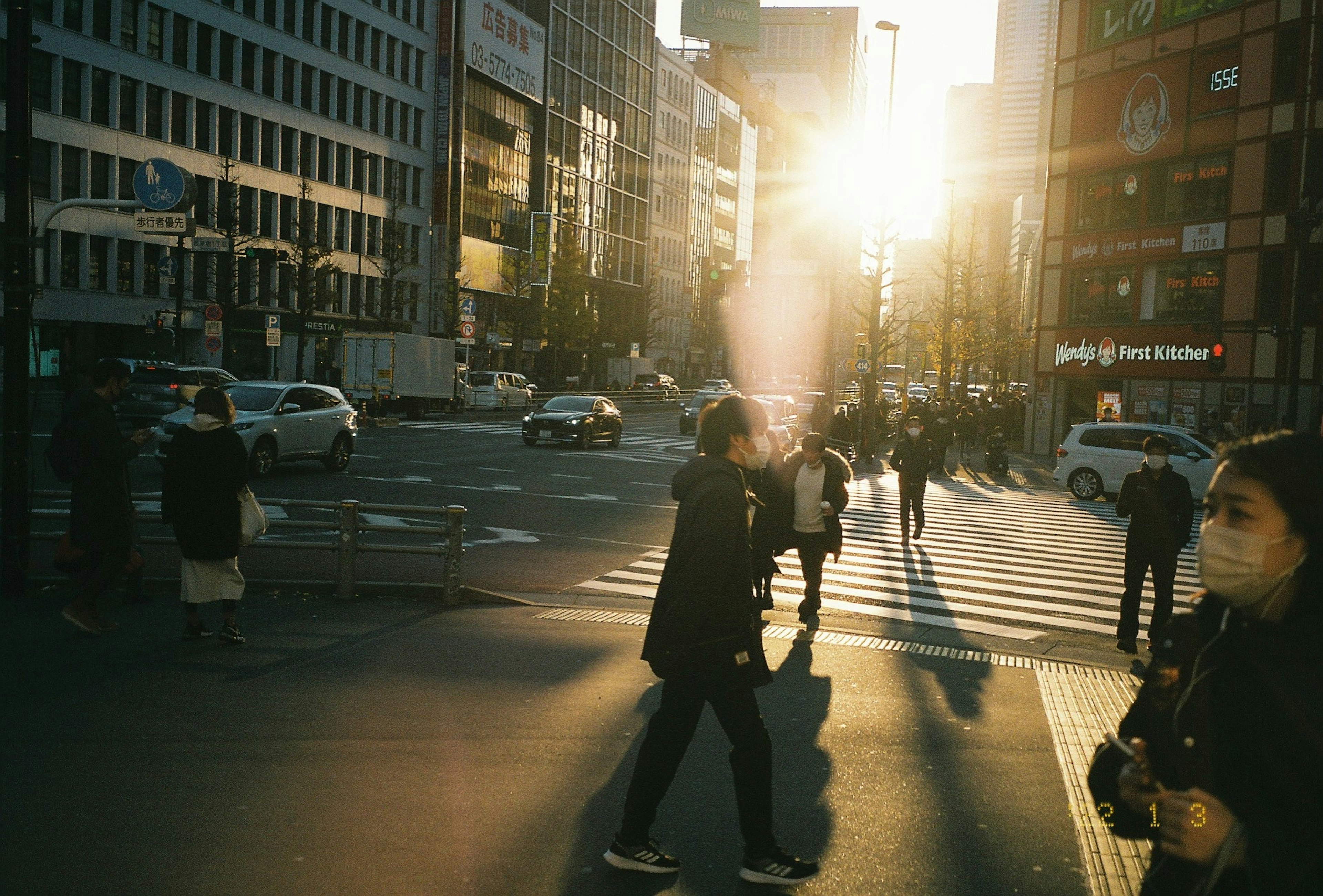 Persone che camminano in un incrocio urbano con luce solare