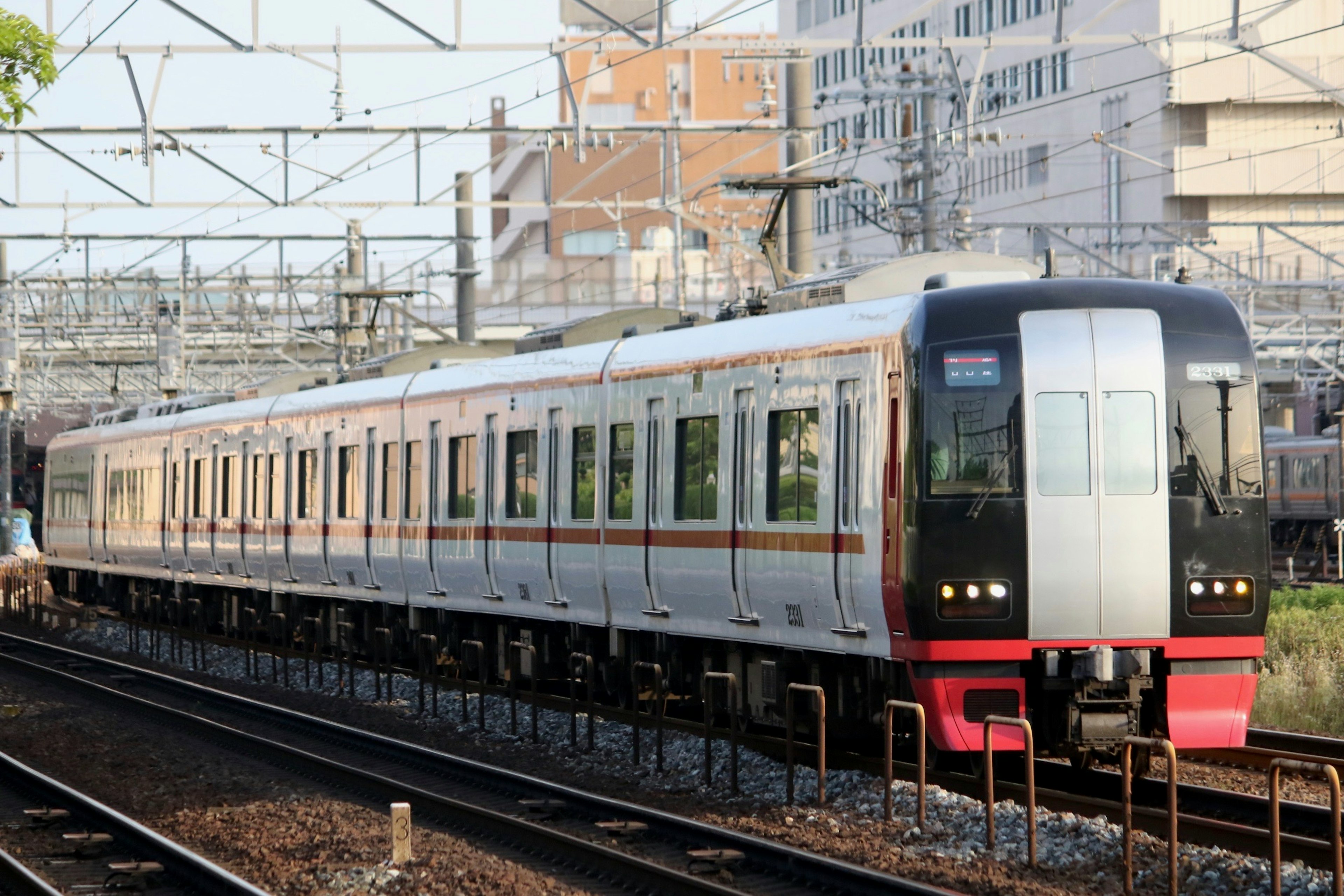 新しいデザインの電車が駅に停車中で周囲に高架線が見える