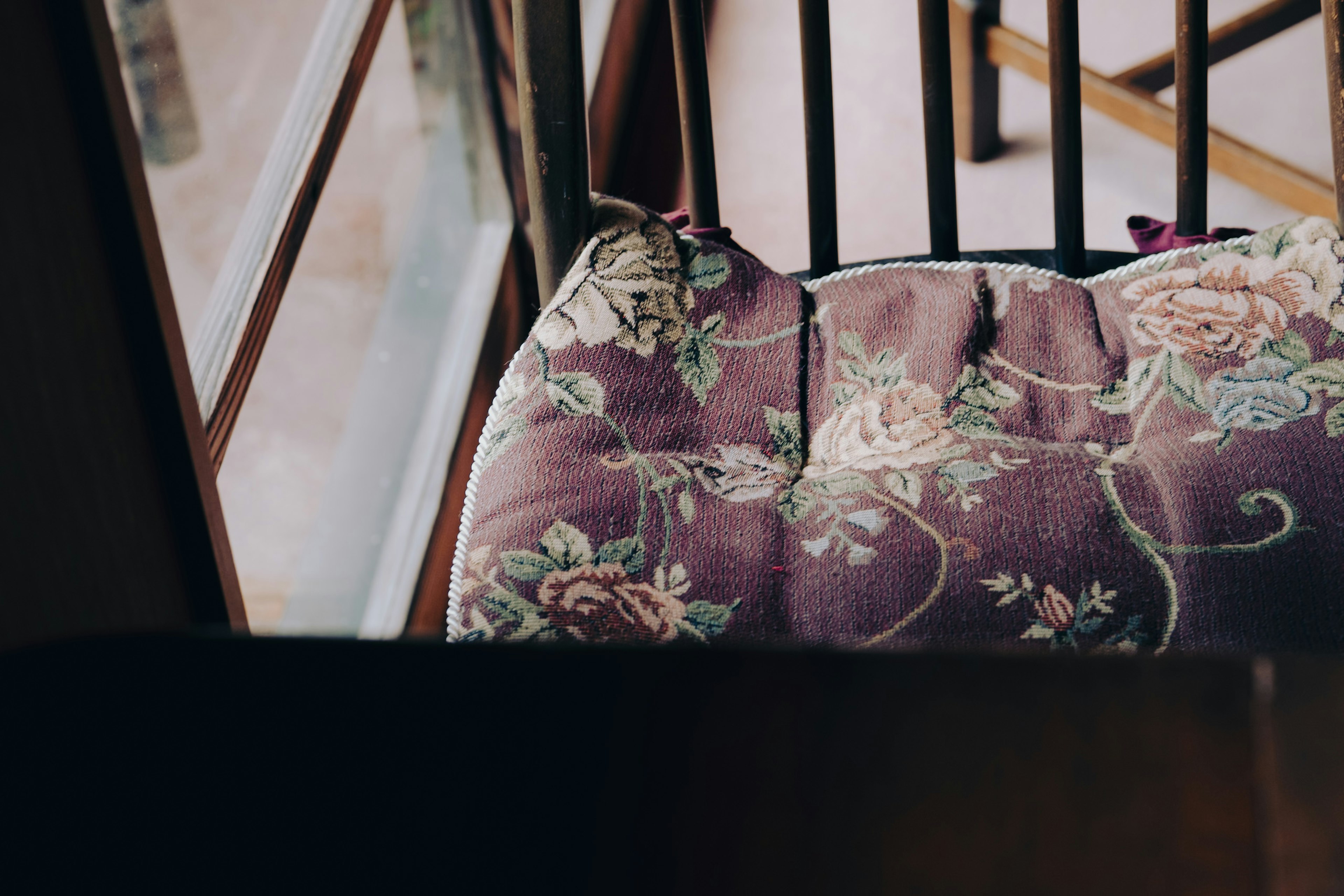 Coussin à motif floral violet sur une chaise avec cadre de fenêtre