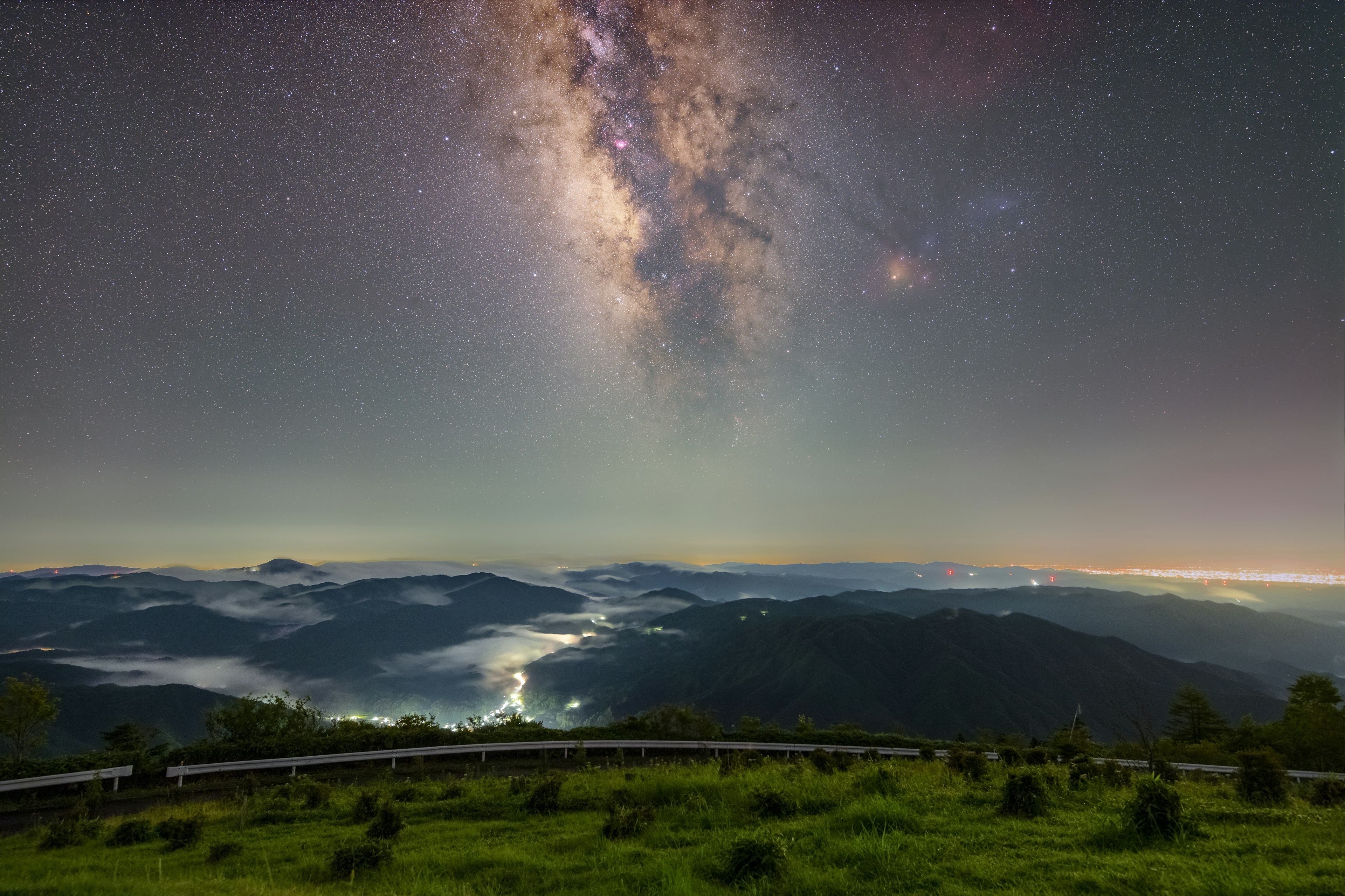 夜空に輝く天の川と霧に覆われた山々の景色