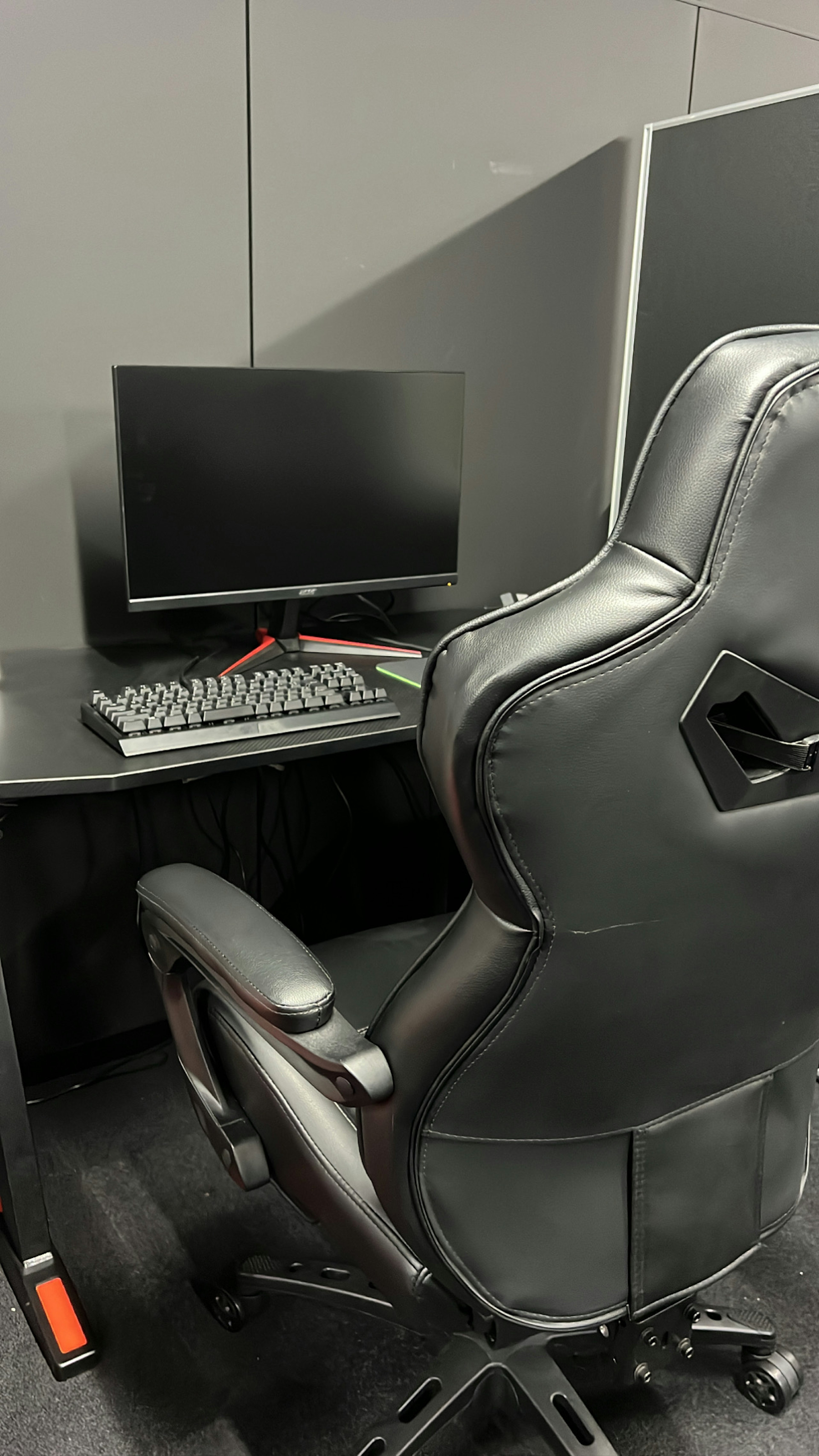 Schwarzer Gaming-Stuhl und Monitor in einem Schreibtisch-Setup