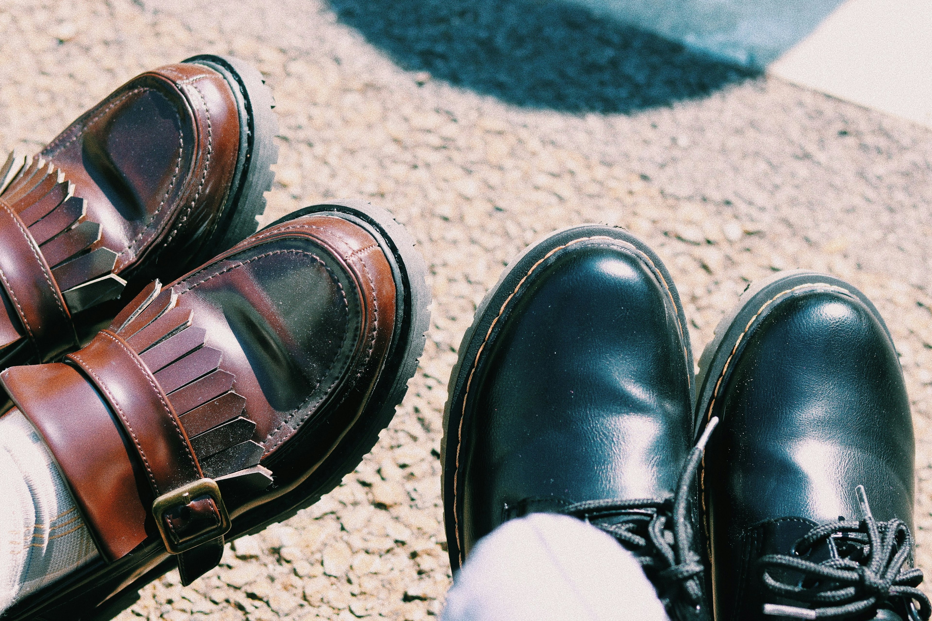 Una foto di due scarpe diverse affiancate una è una scarpa in pelle marrone e l'altra è un stivale nero