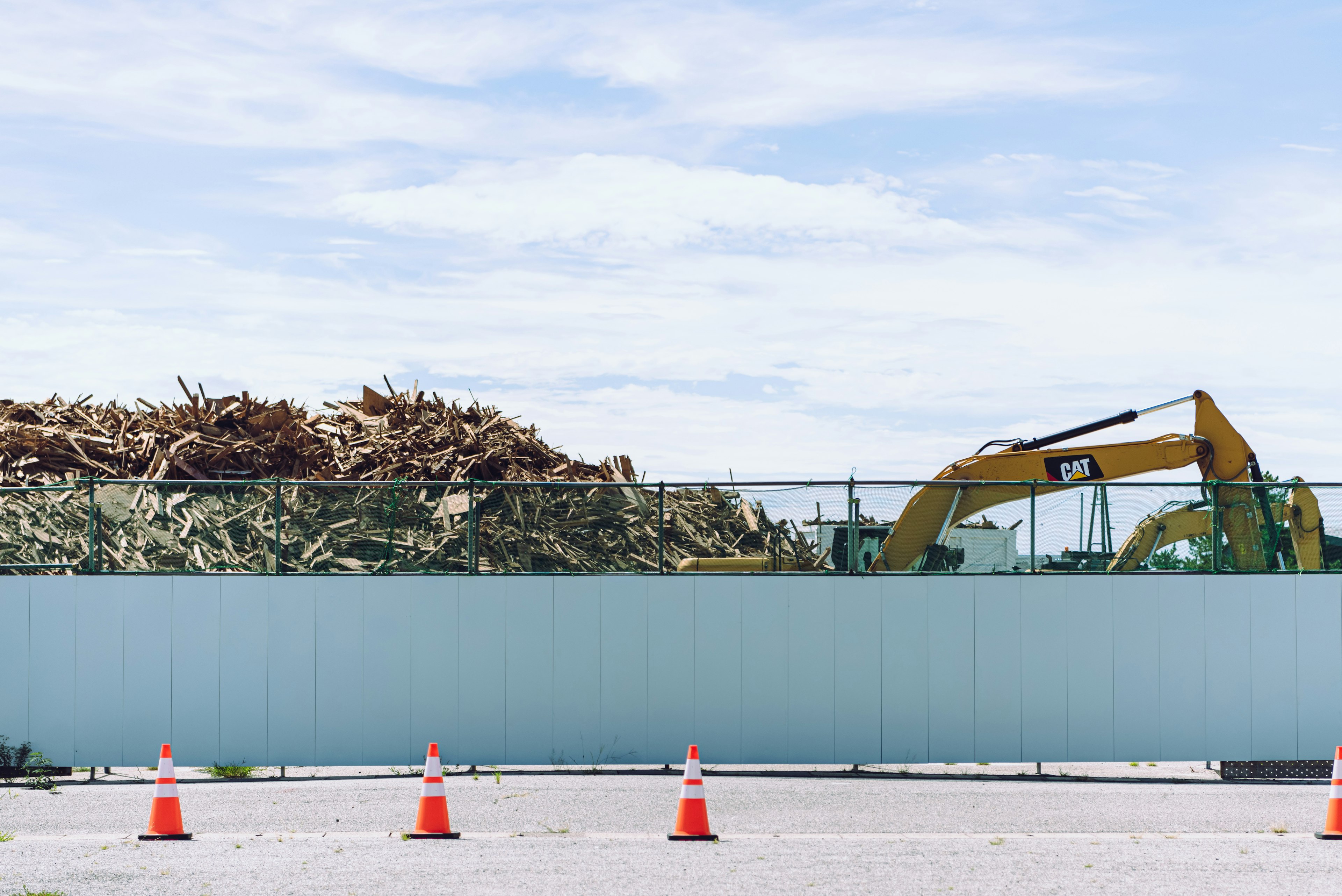 Construction site featuring a pile of wood and heavy machinery