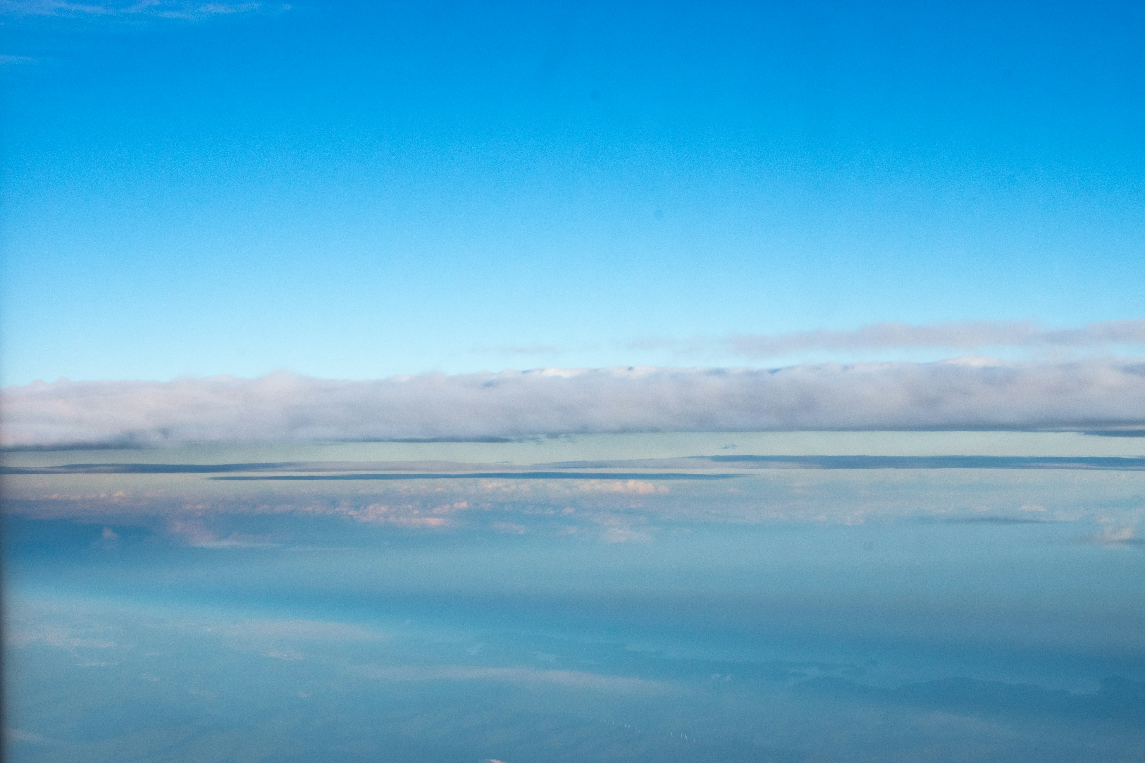 A panoramic view of the ocean under a clear blue sky with clouds