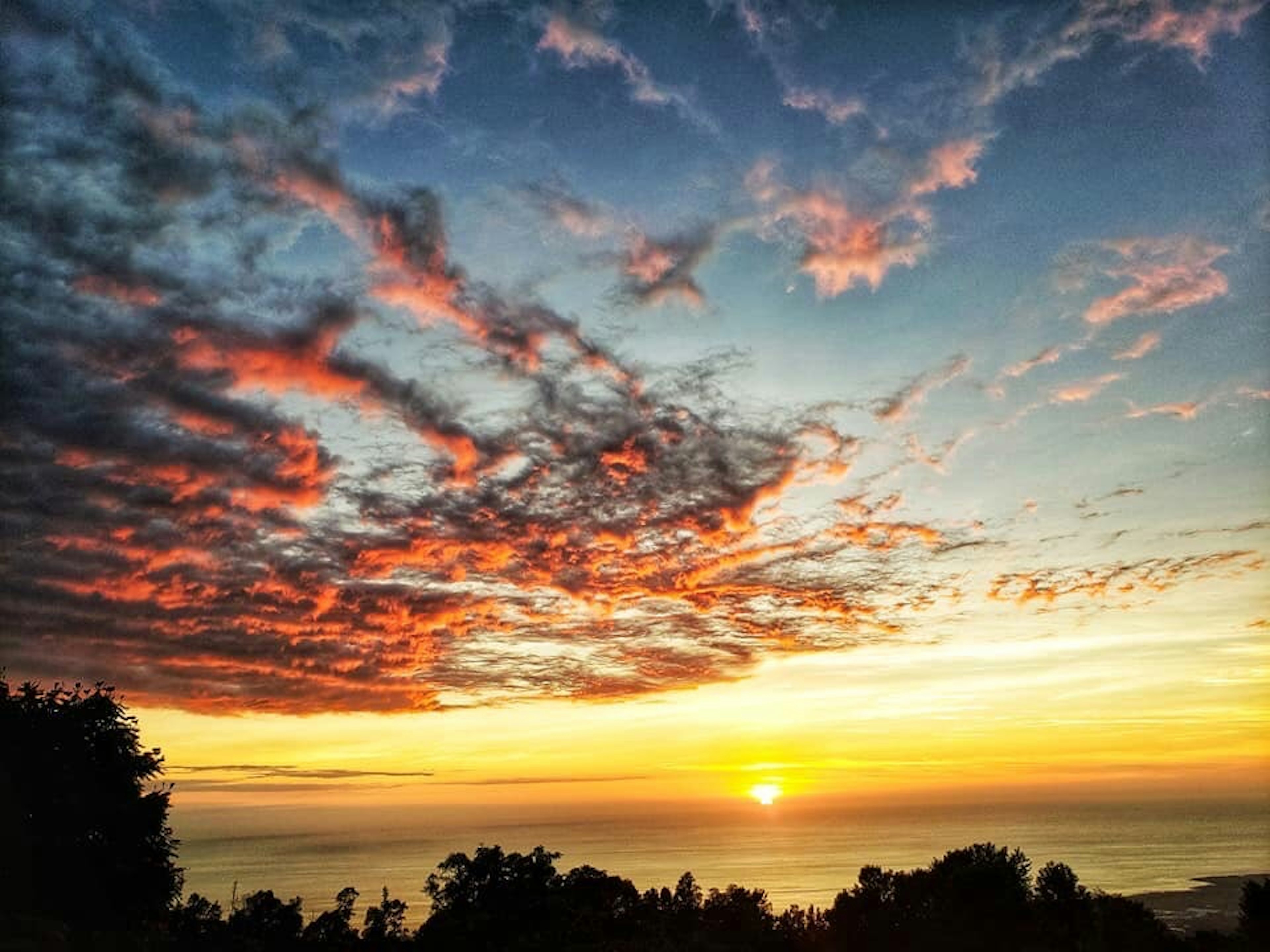 美しい夕焼けと色とりどりの雲が広がる海の風景