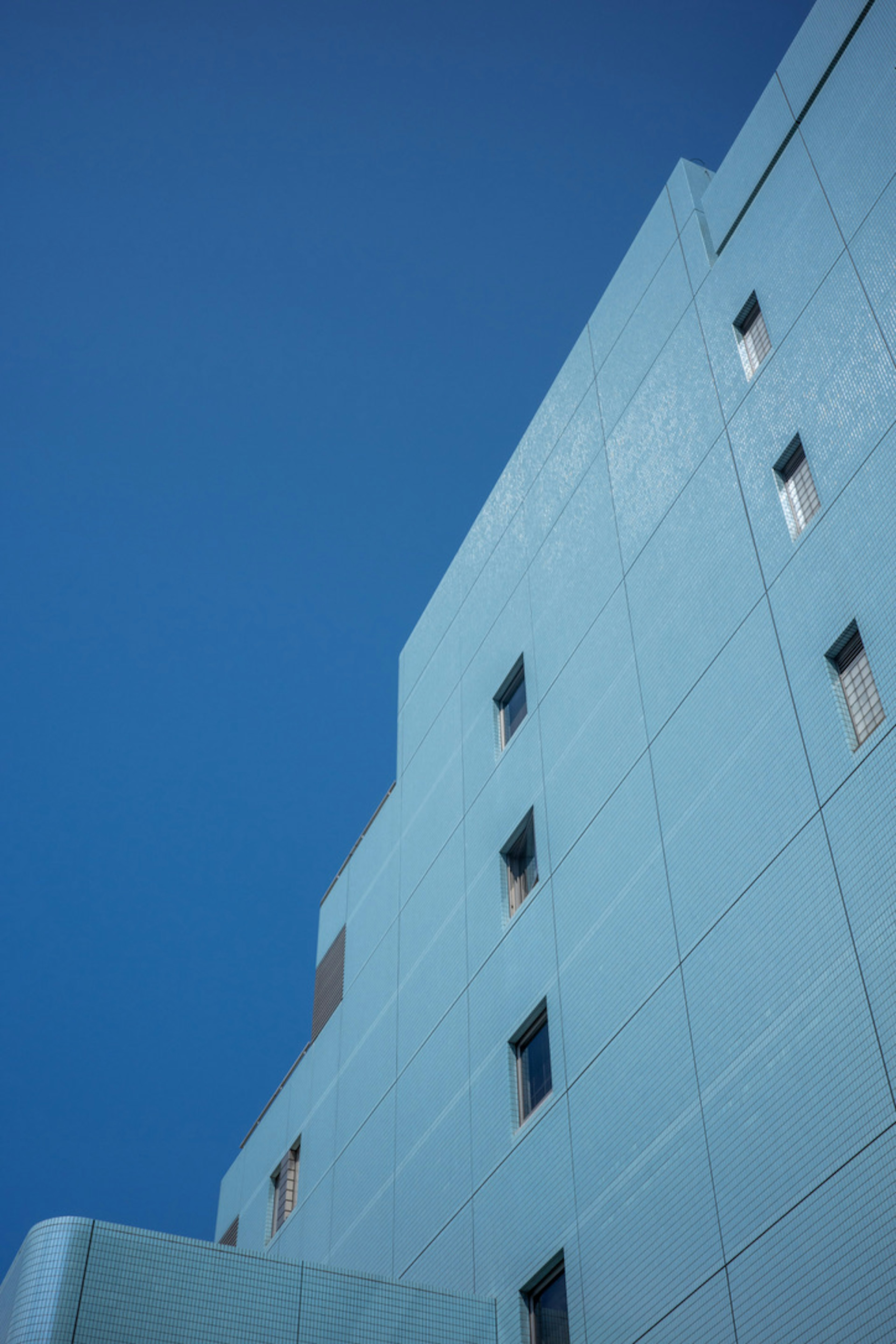 Seitenansicht eines blauen Gebäudes vor einem klaren blauen Himmel