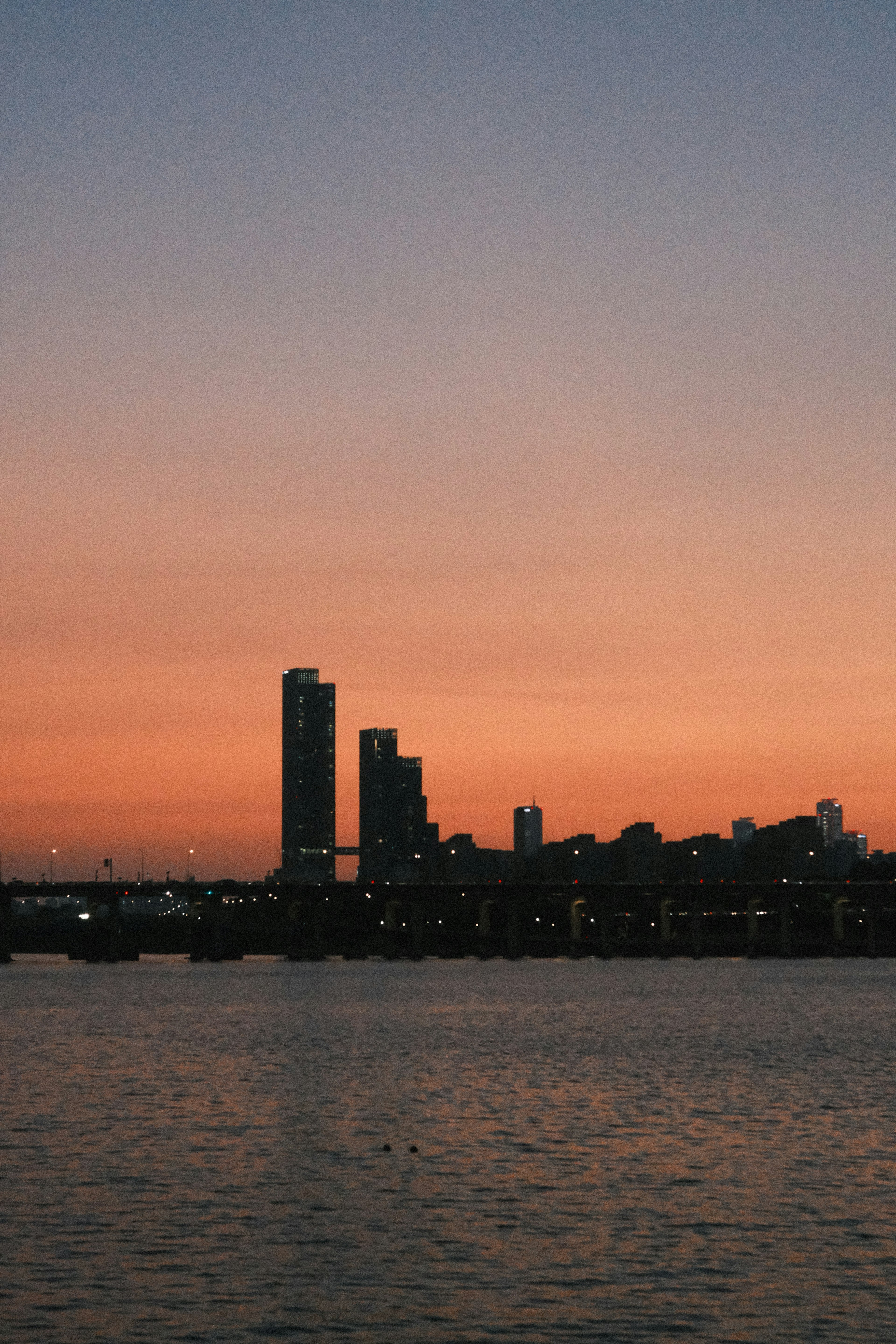 Silhouette of skyscrapers against a sunset sky