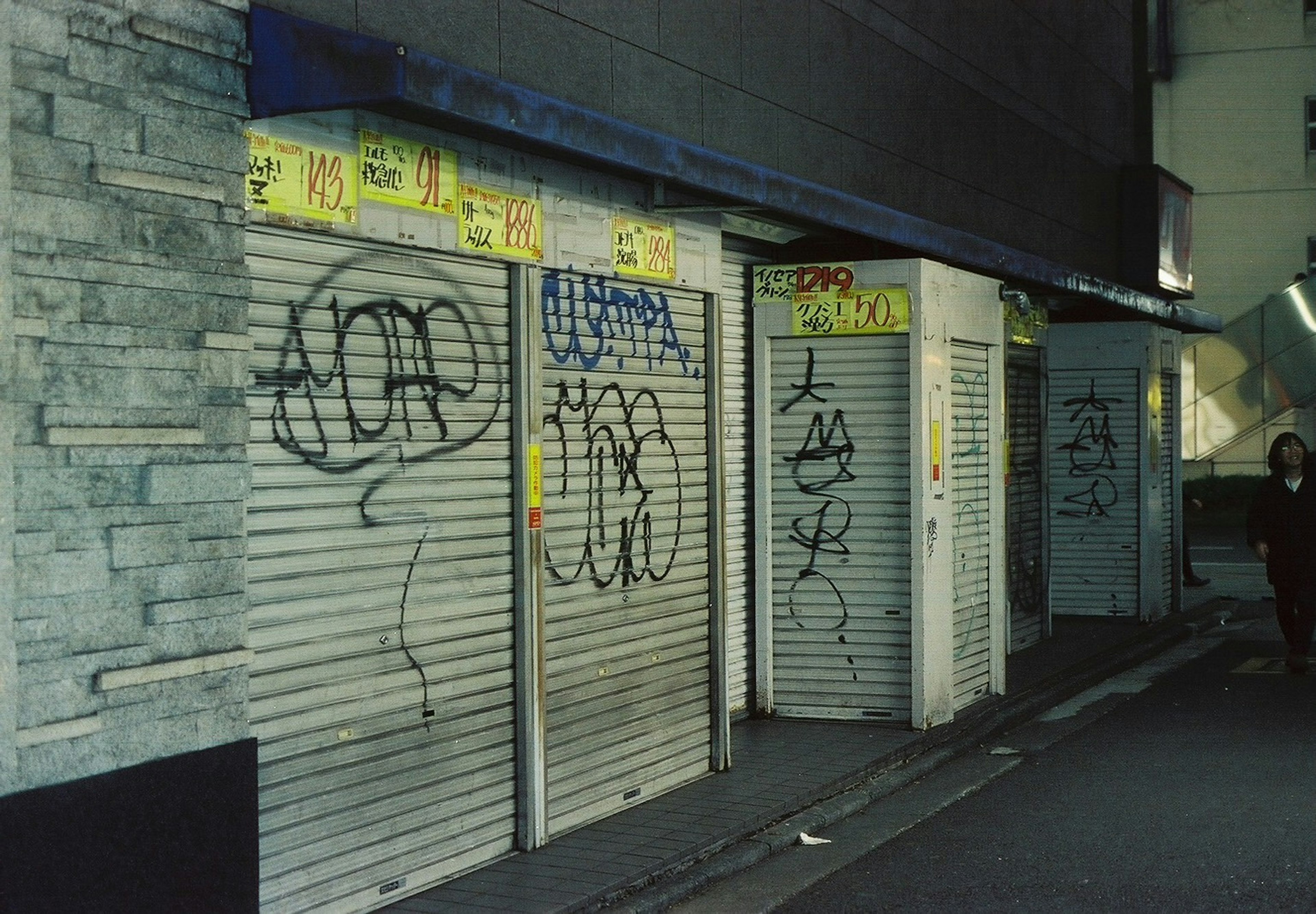 Außenansicht von geschlossenen Geschäften mit Graffiti und Tags in einer dunklen Gasse