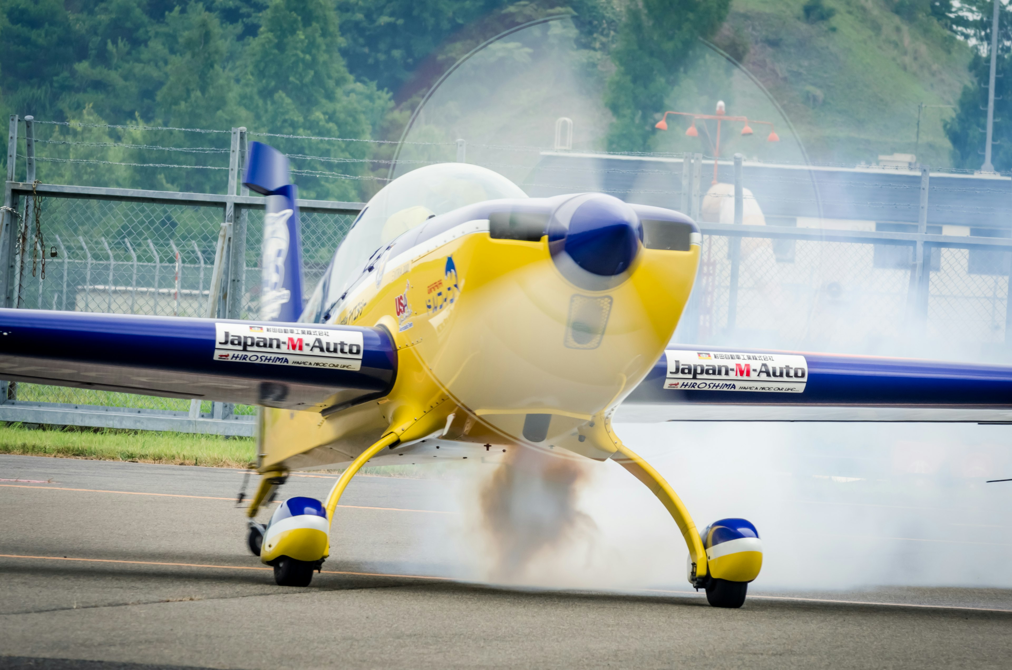 黄色い飛行機が煙を上げながら滑走路で準備中