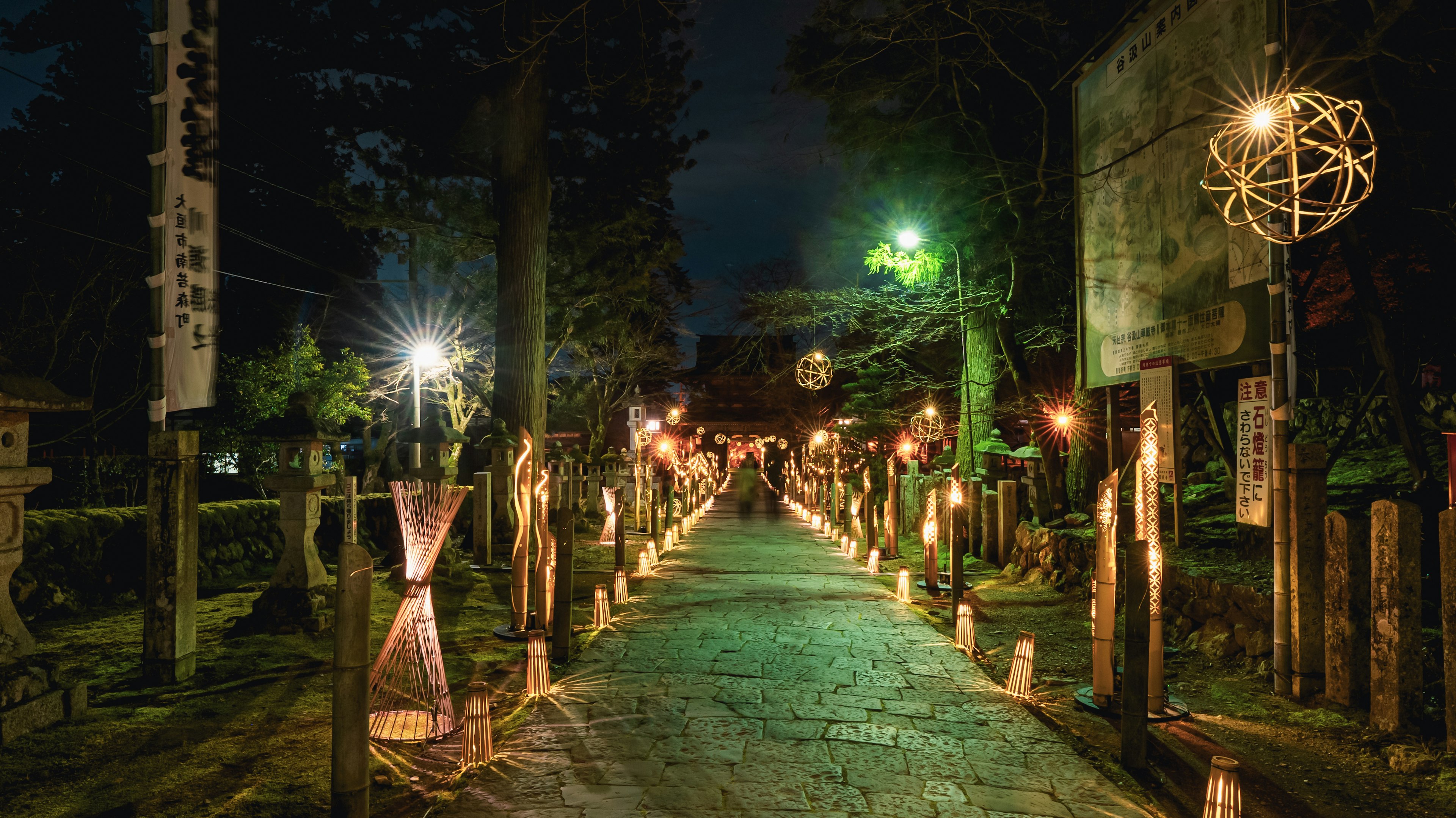 夜の神社の参道に灯りがともる風景