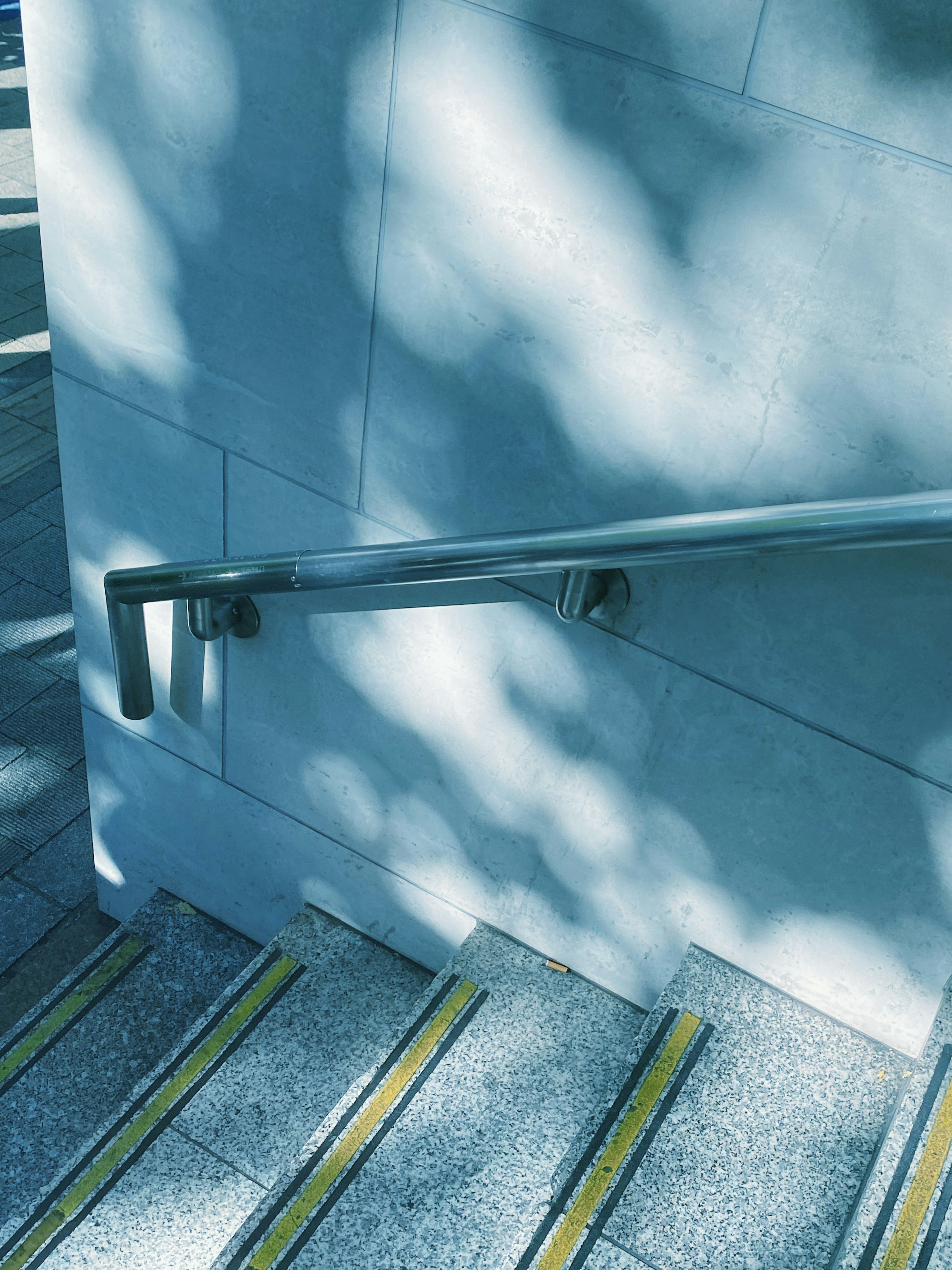 Foto de una escalera con tono azul y pasamanos Sombras de luz proyectadas en los escalones