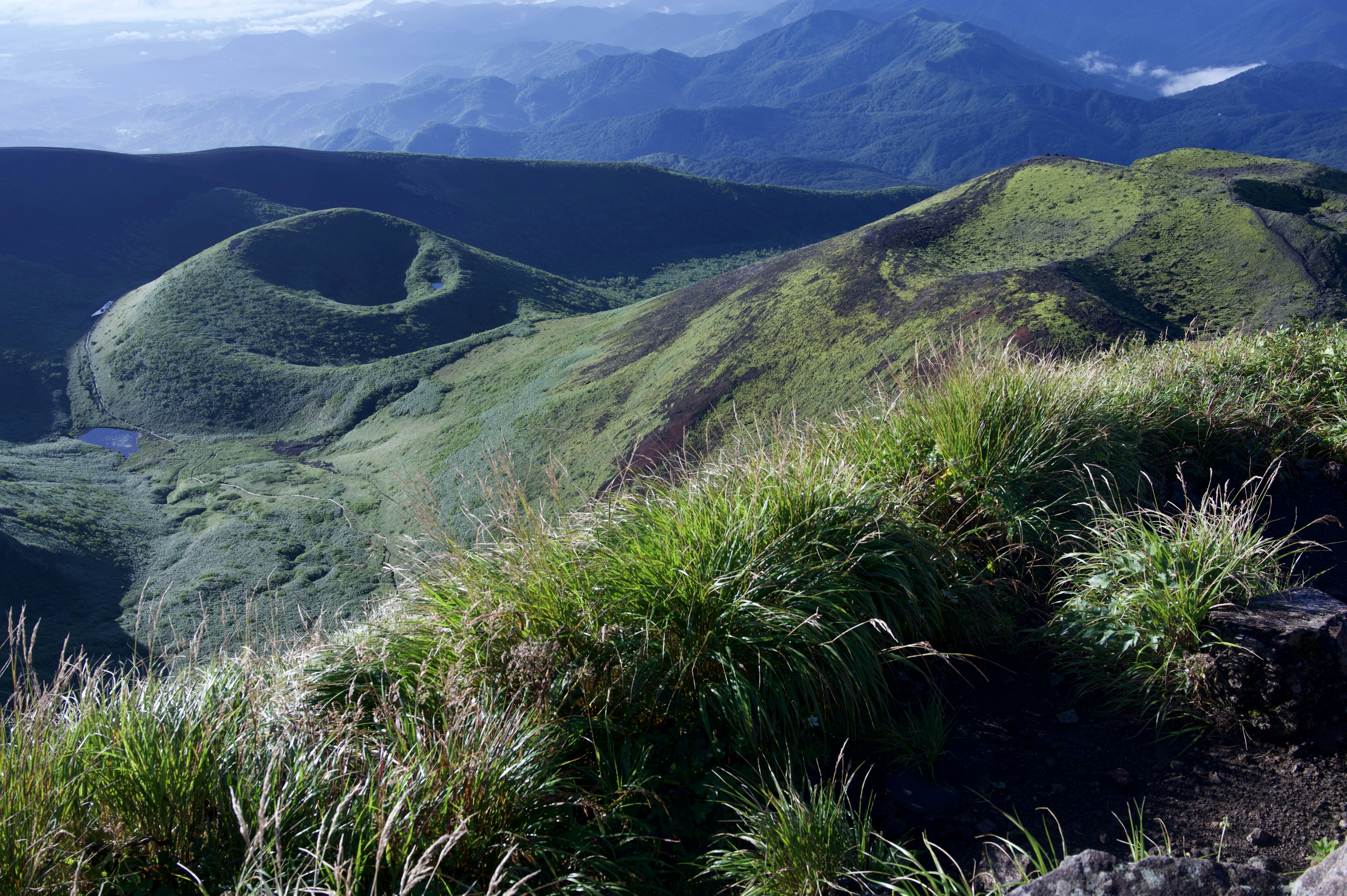 Paisaje montañoso verde con picos distantes visibles