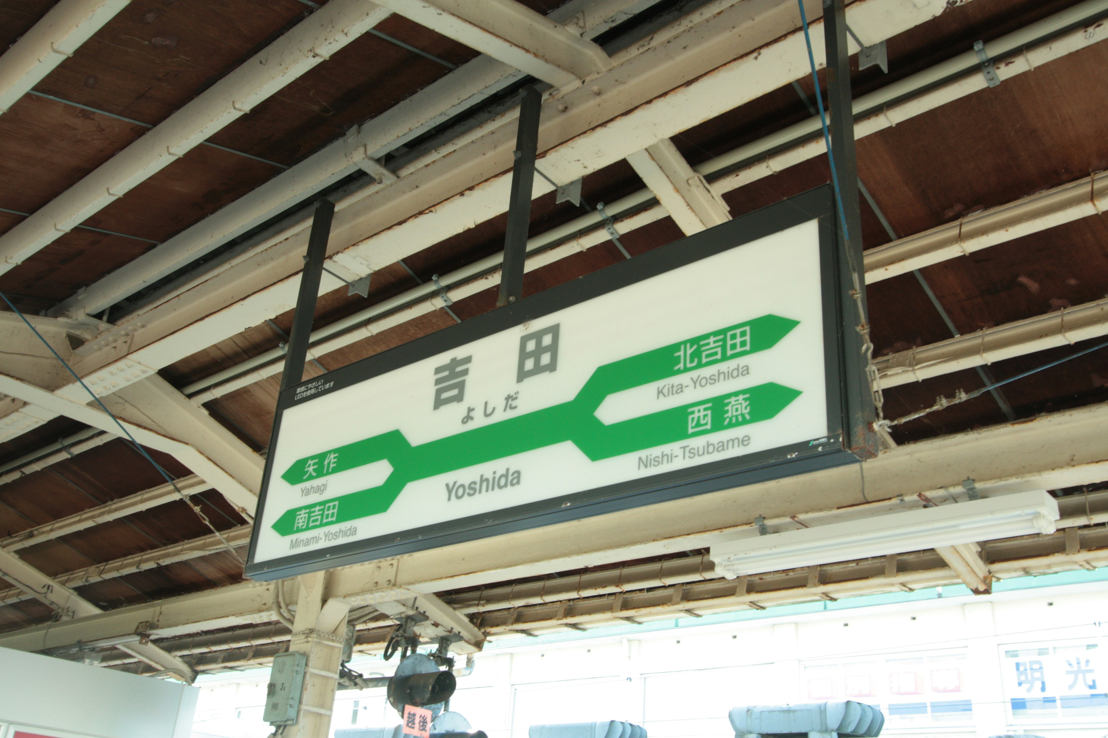 Cartel de la estación Aota con diseño verde que muestra el nombre de la estación y la información de las líneas