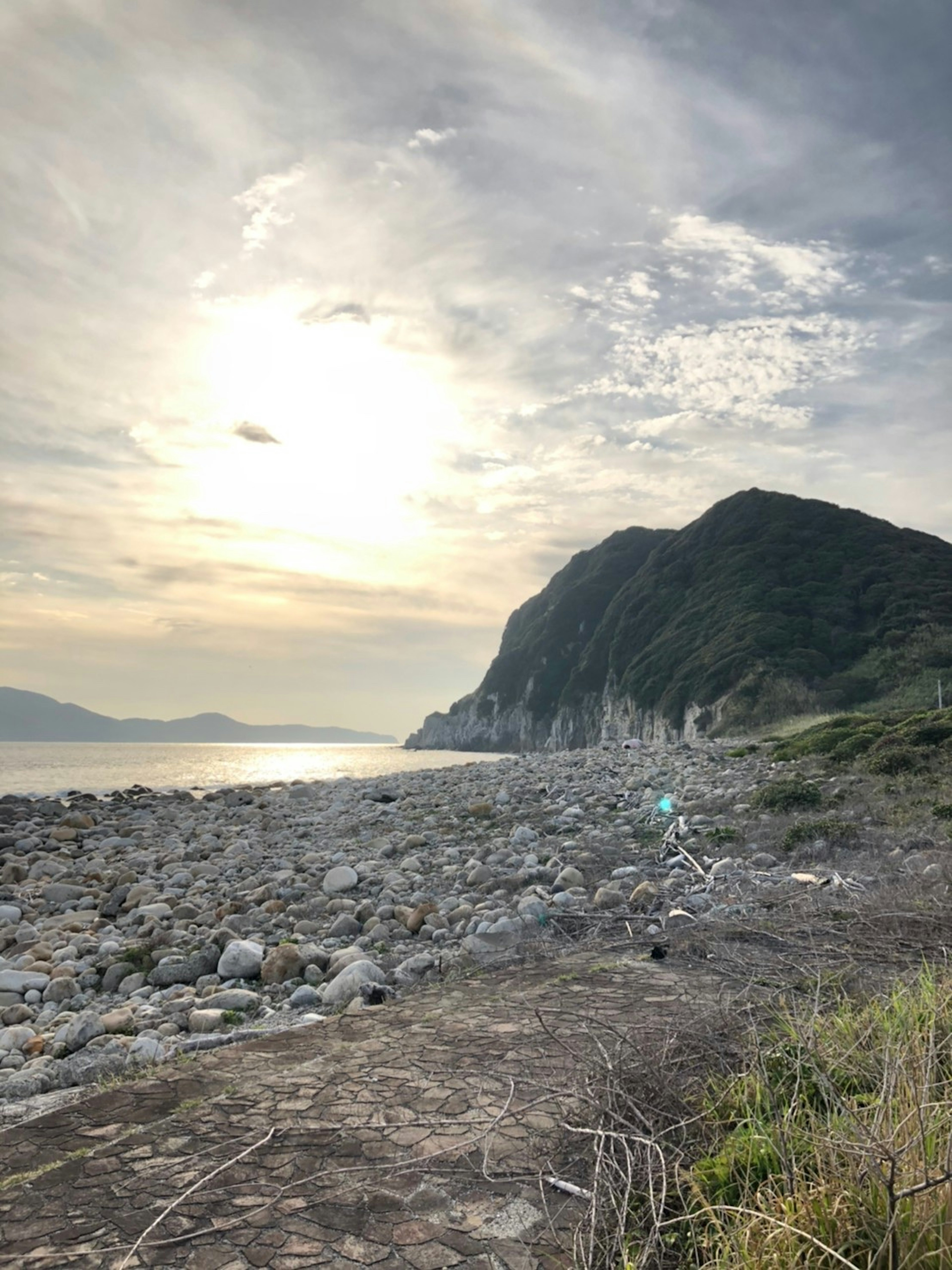 海岸線に沿った岩場と山々の風景夕日が海に反射している