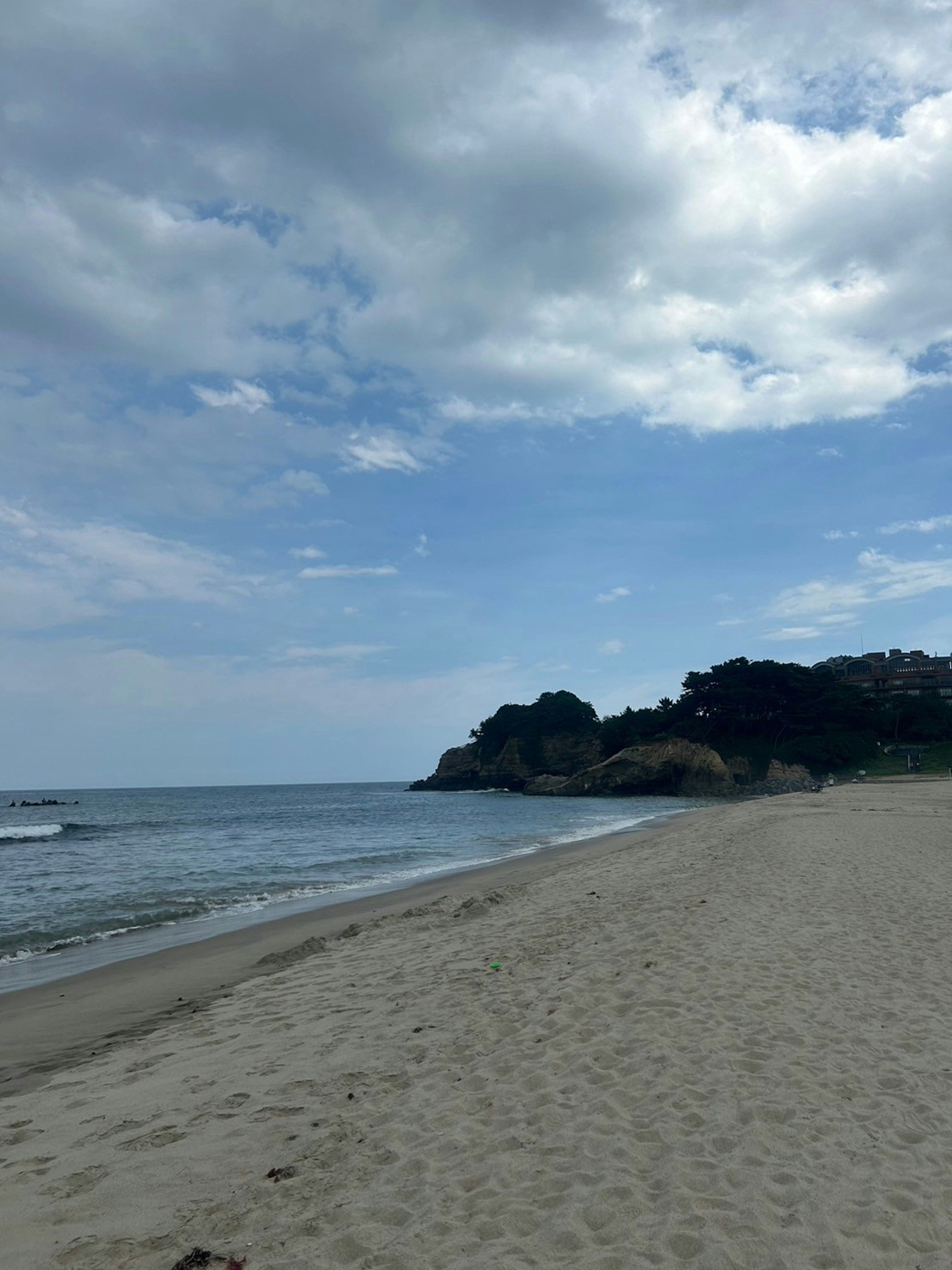 Una escena de playa serena con aguas tranquilas y una orilla de arena Nubes dispersas en el cielo