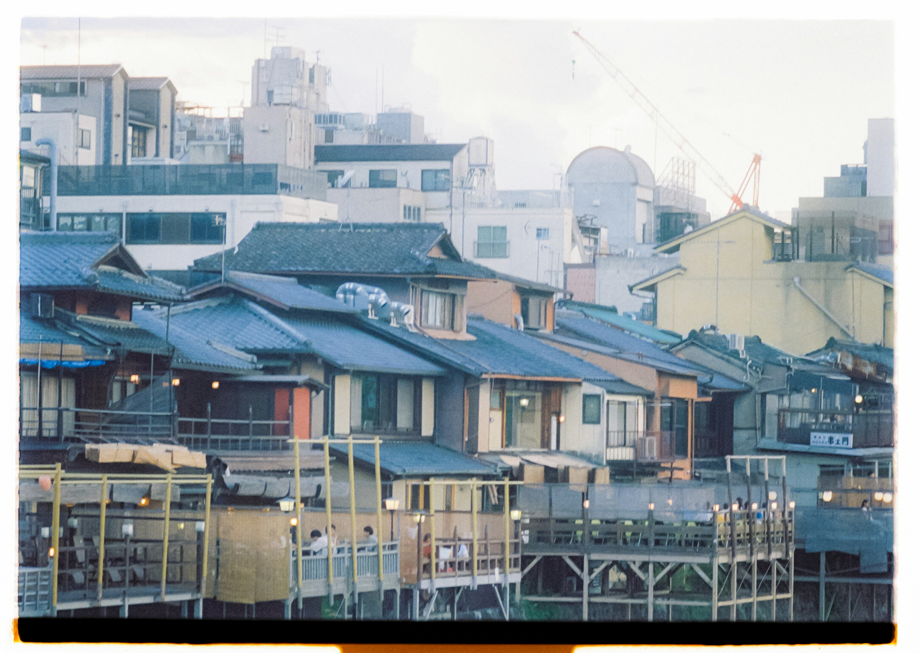 Traditional Japanese houses lined up near the waterfront with modern buildings in the background