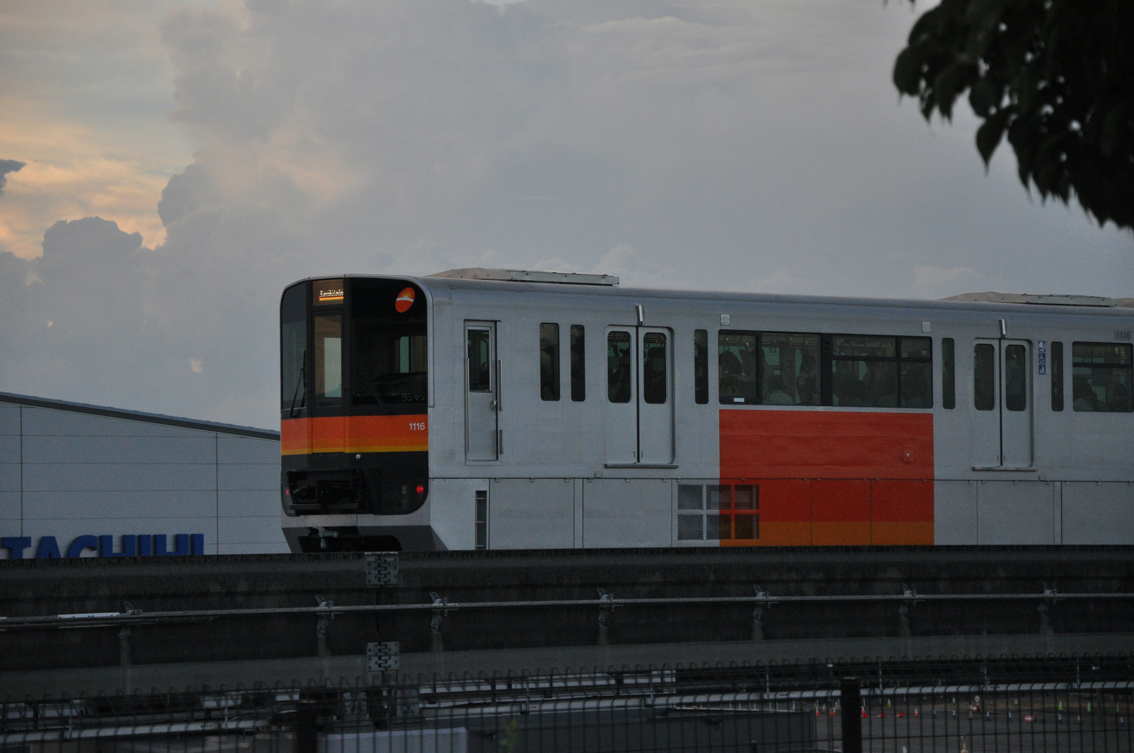 A white and orange train passing against a scenic backdrop