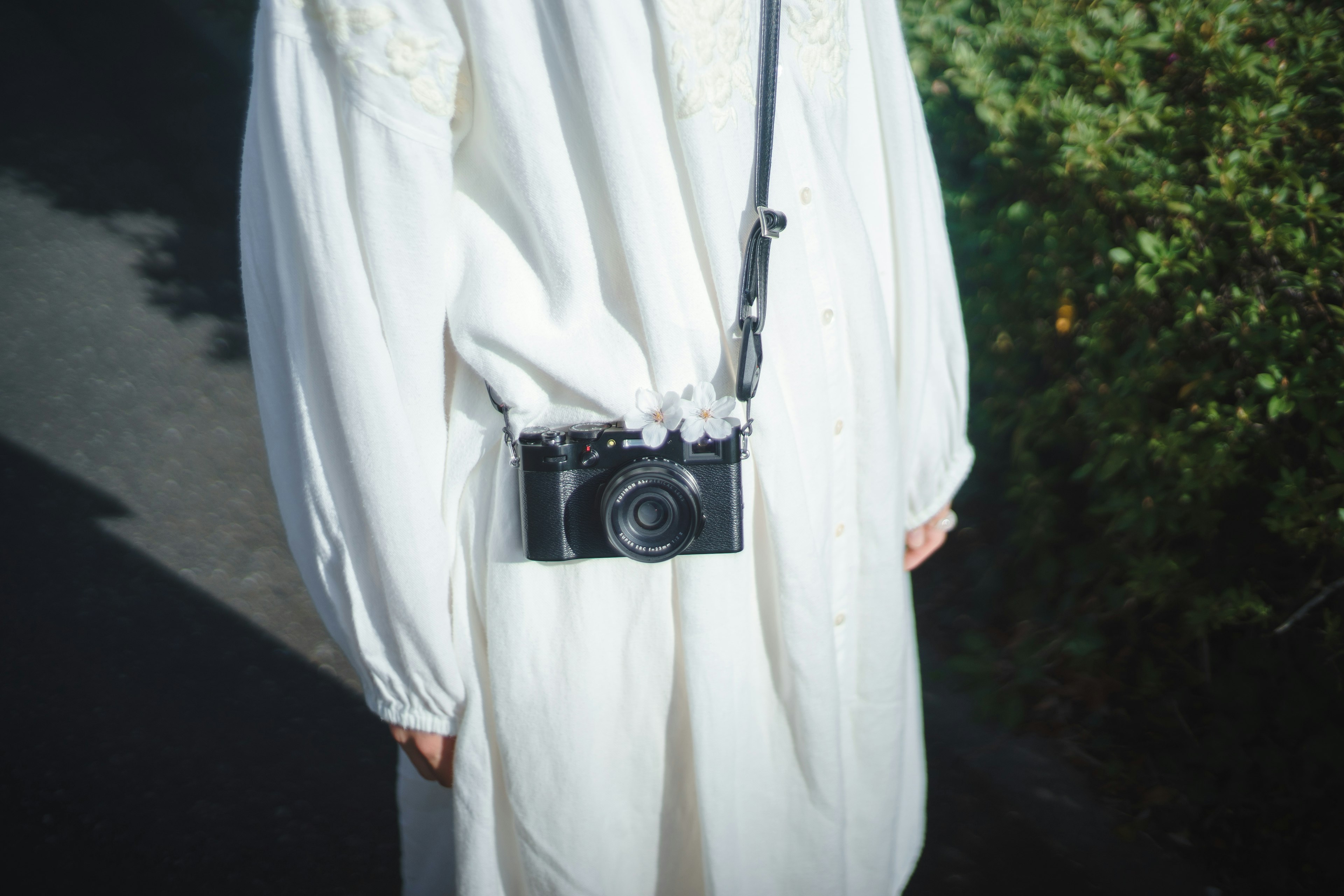 Una persona vestida con un atuendo blanco con una cámara colgada del hombro