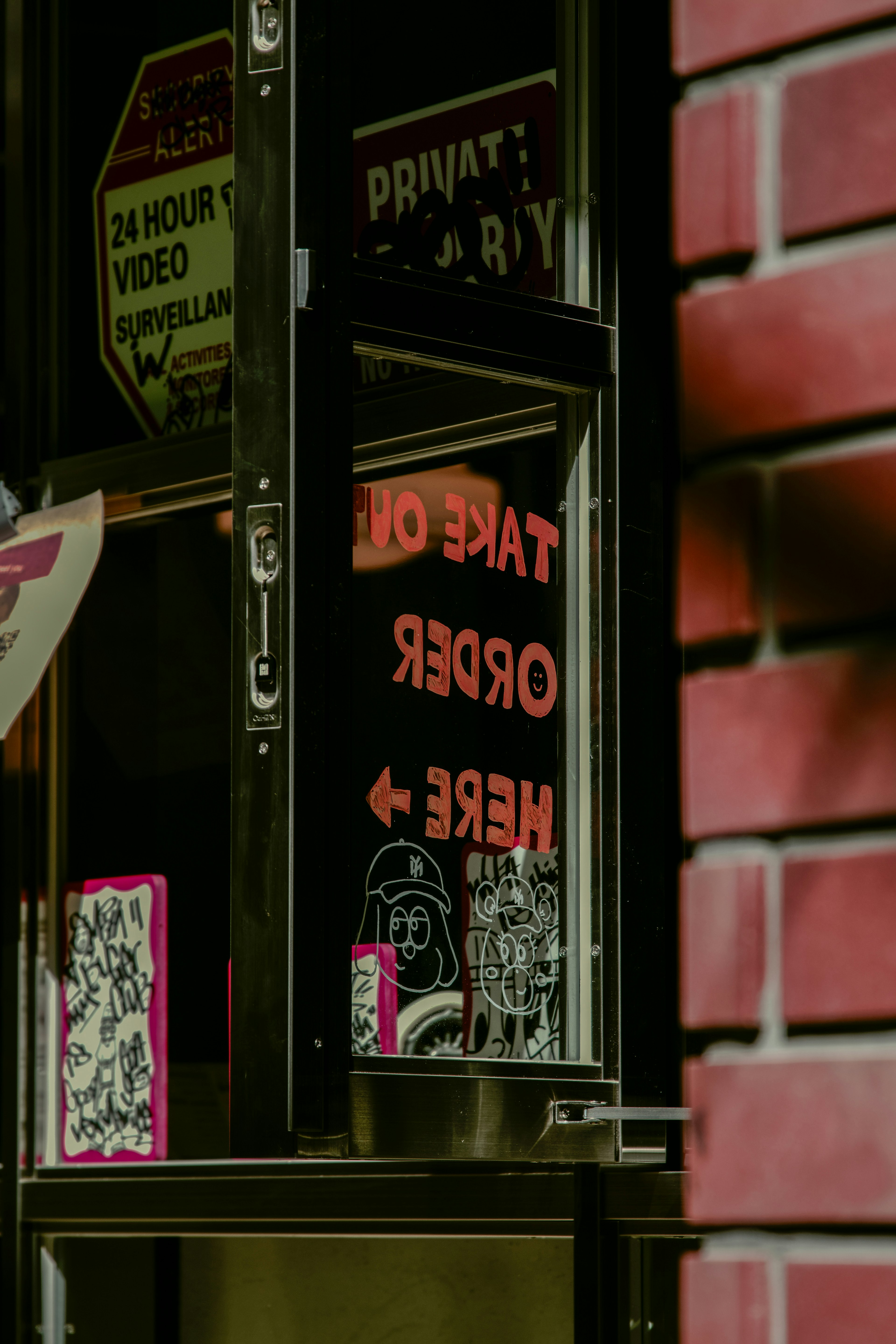 Image featuring a takeout window with red signage and a brick wall